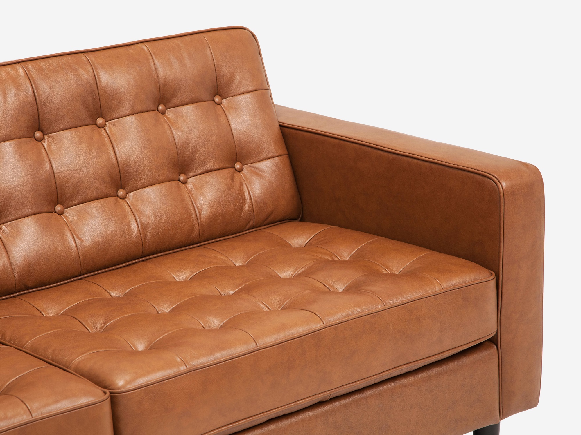 Detail view of leather tufted apartment couch with black ash legs