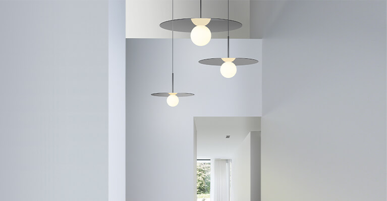 three aluminum round pendants hang from a large hallway. Link to Pablo Designs category page