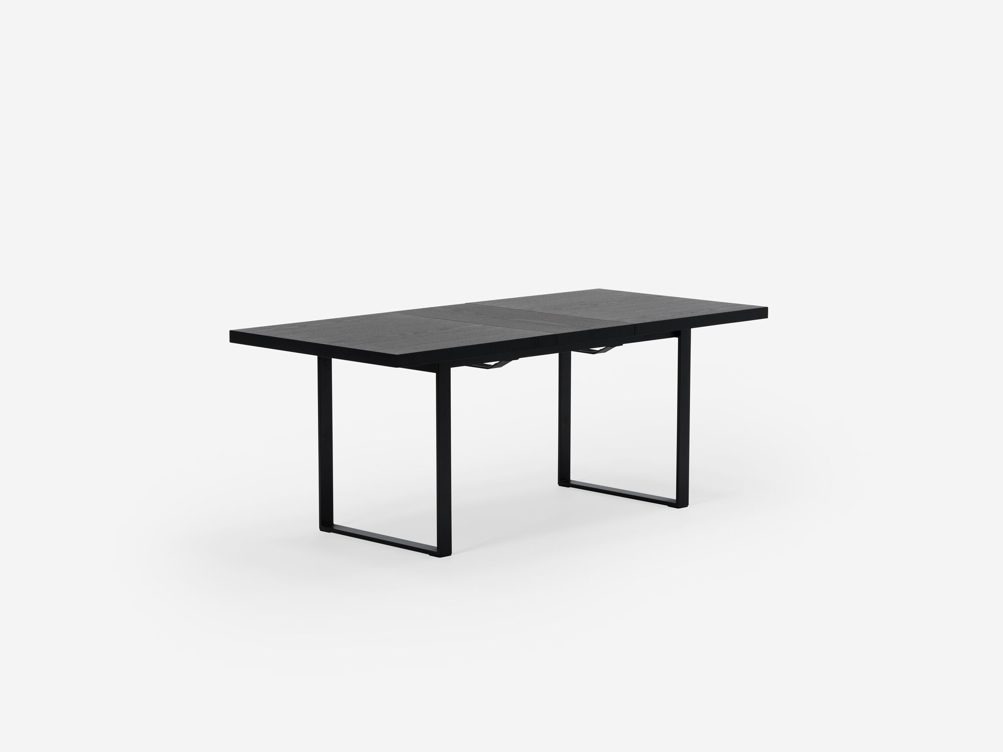 Corner view of expandable dining table with black legs, black top and one leaf