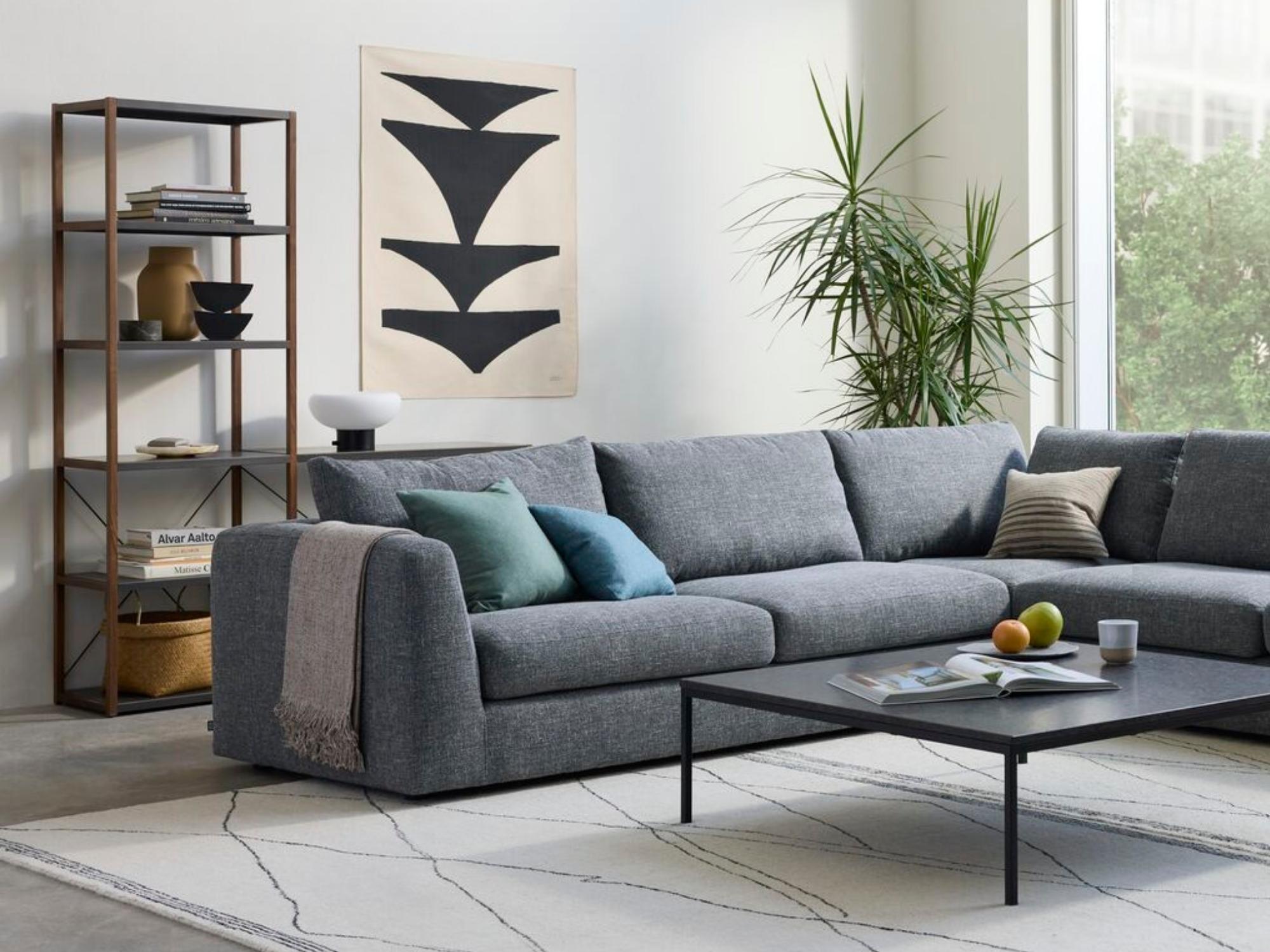 Walnut and charcoal open bookshelf behind gray upholstered sectional