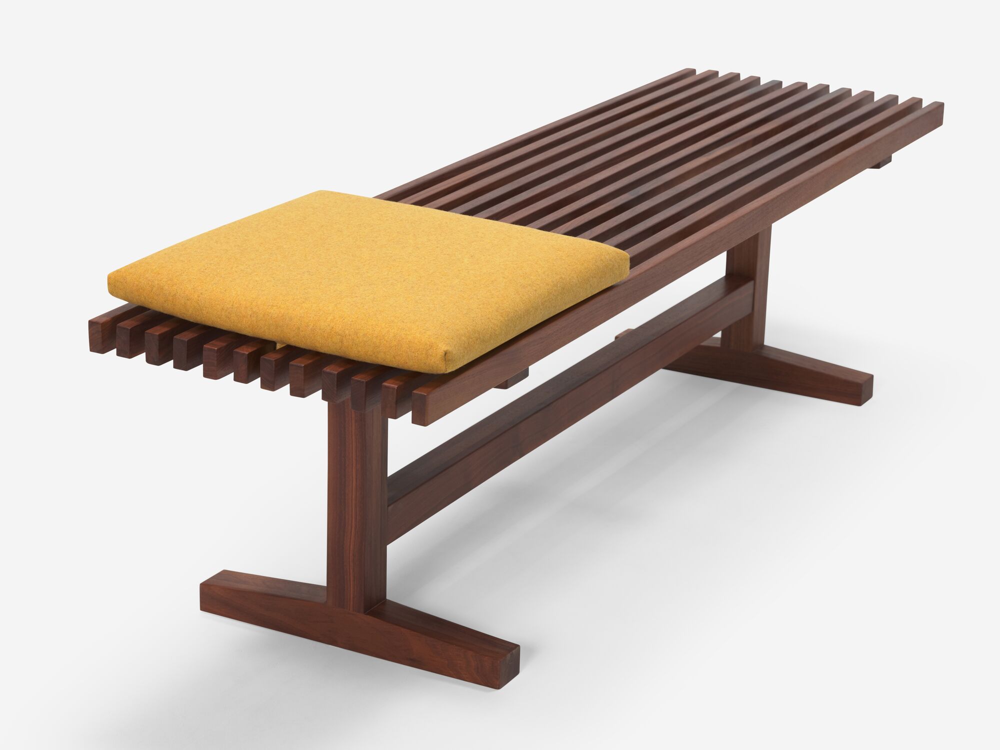 Front angle view of square yellow cushion on walnut bench