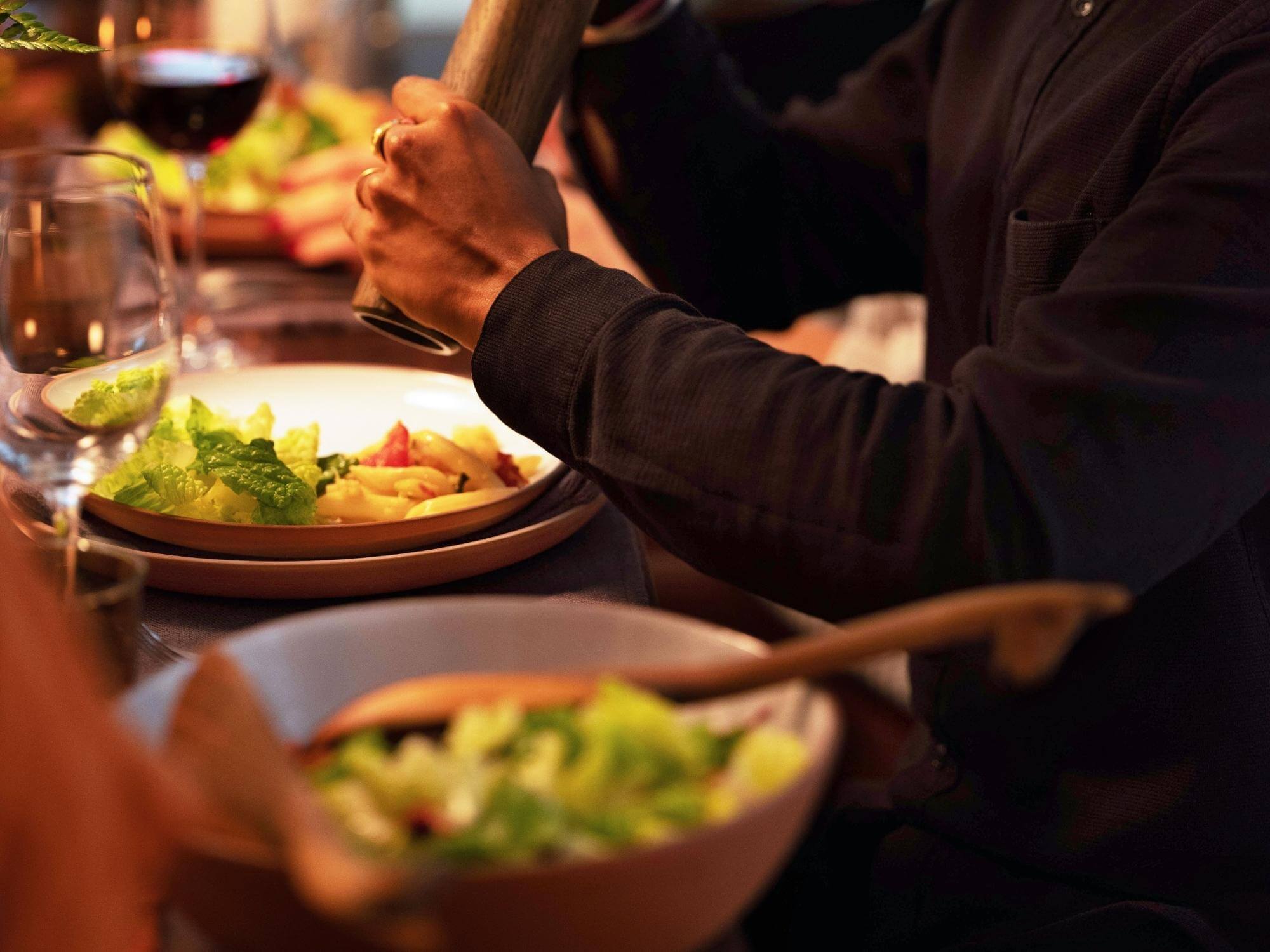 Man seasoning dinner on gray stone plate near matching serving bowl