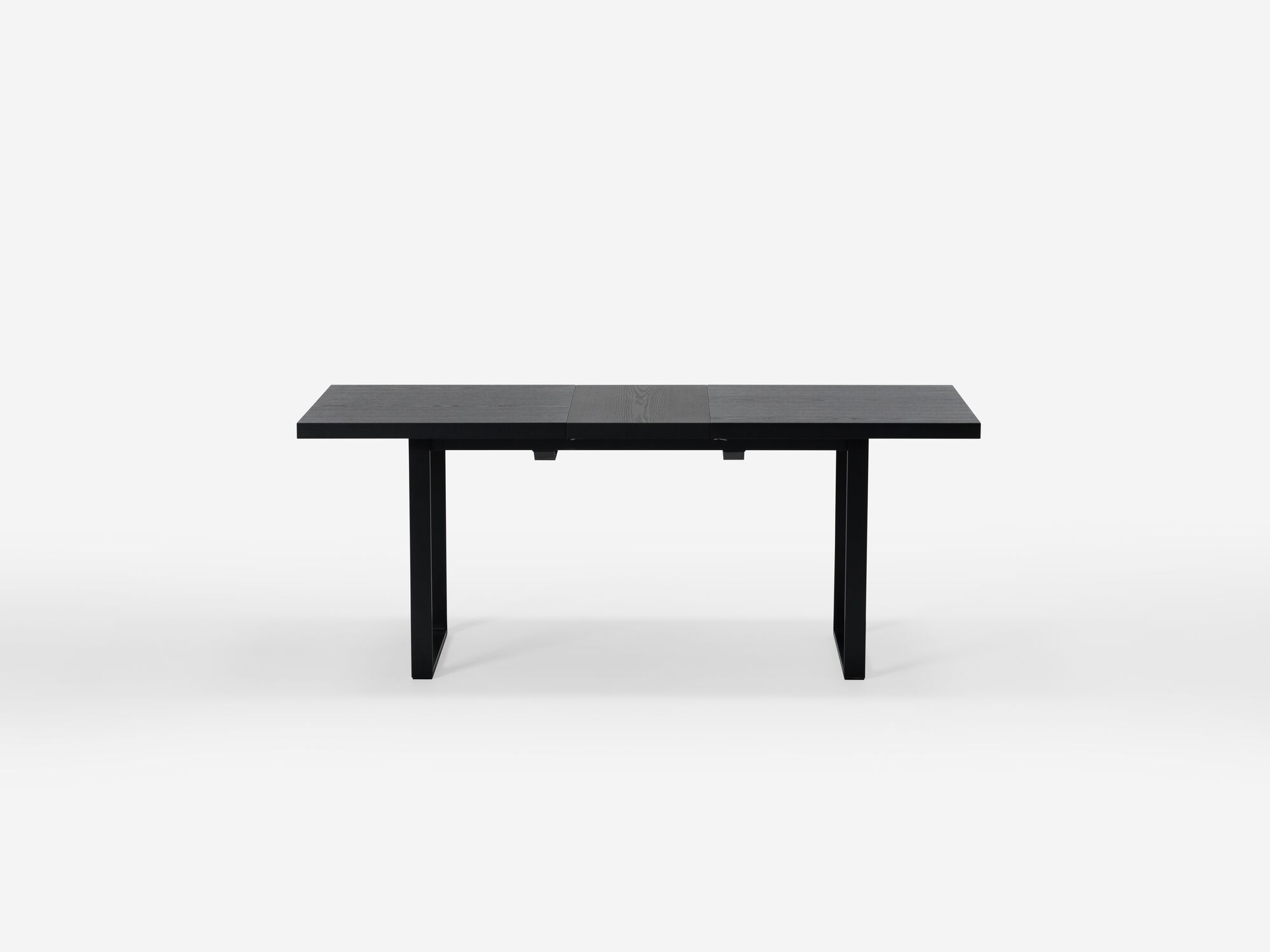 Expandable dining table with black legs and black top with one leaf side view