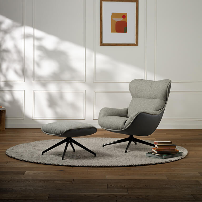 An accent chair and matching ottoman are displayed in a living room setting. Link to Arie Exclusive