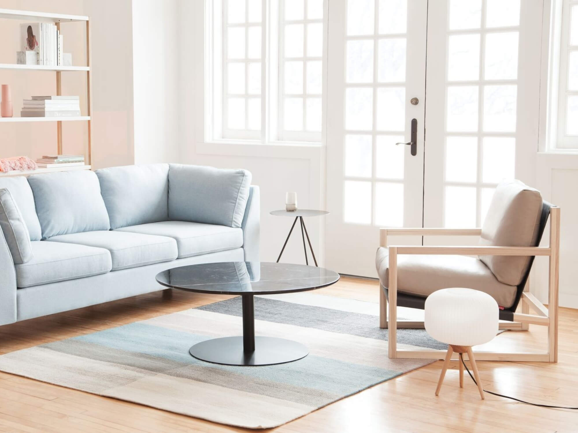 Lamp with white shade and oak legs in corner of living space