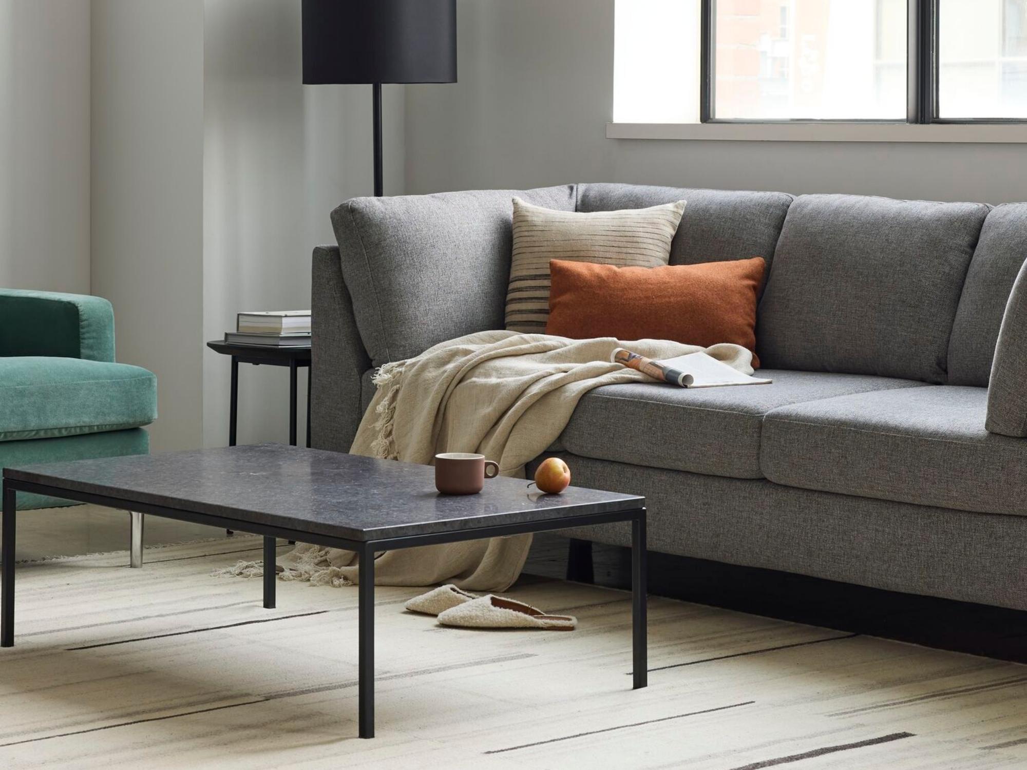 Beige linen throw on grey sofa with green accent chair