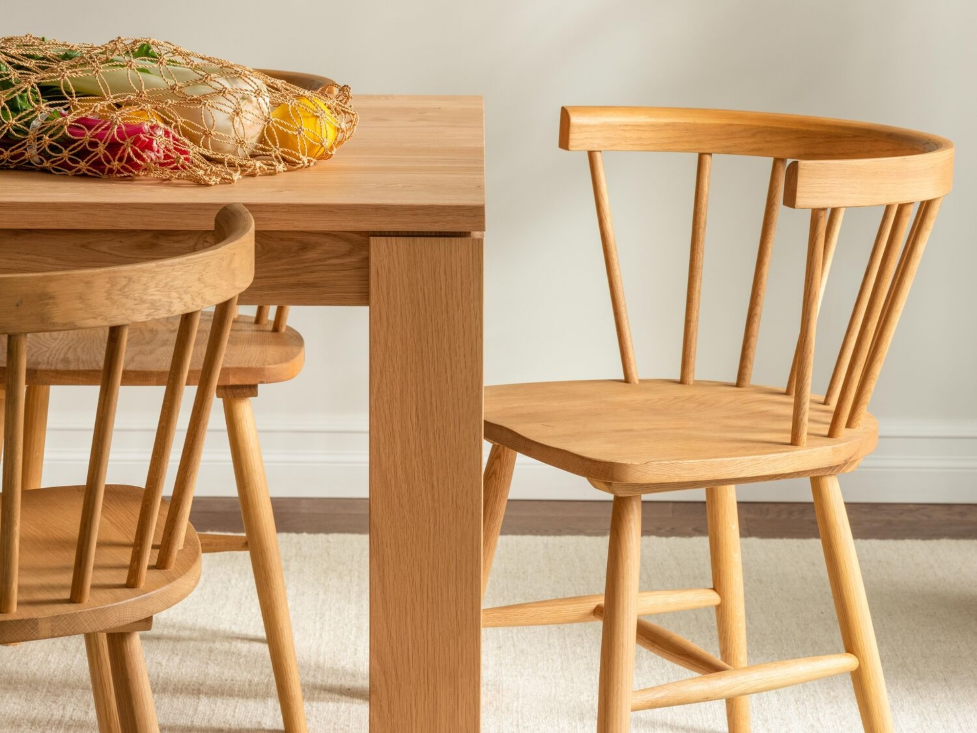 Oak armchairs at a matching dining room table with a mesh bag of produce on it