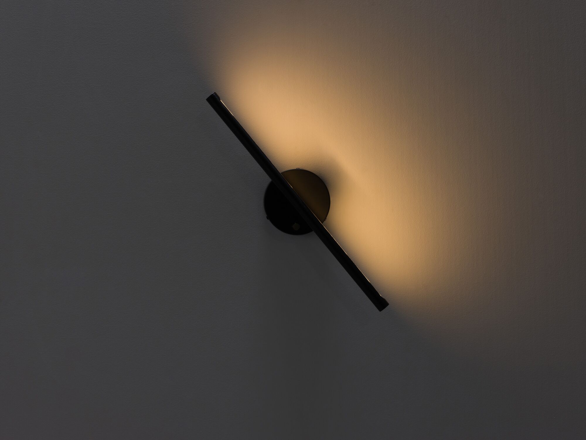Angled black slim wall lamp with light on front view