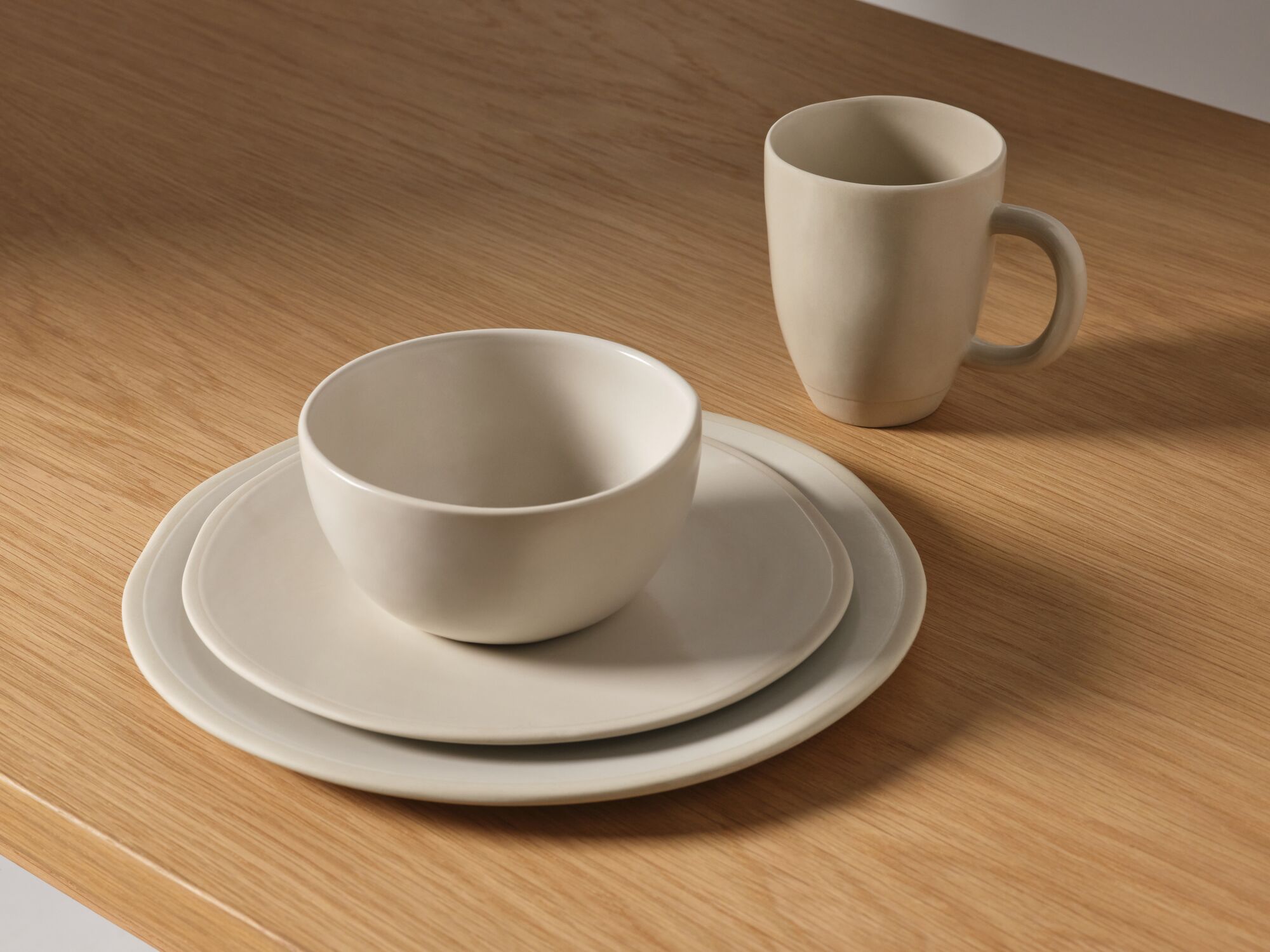 Stoneware bowl with plates and mug on oak counter