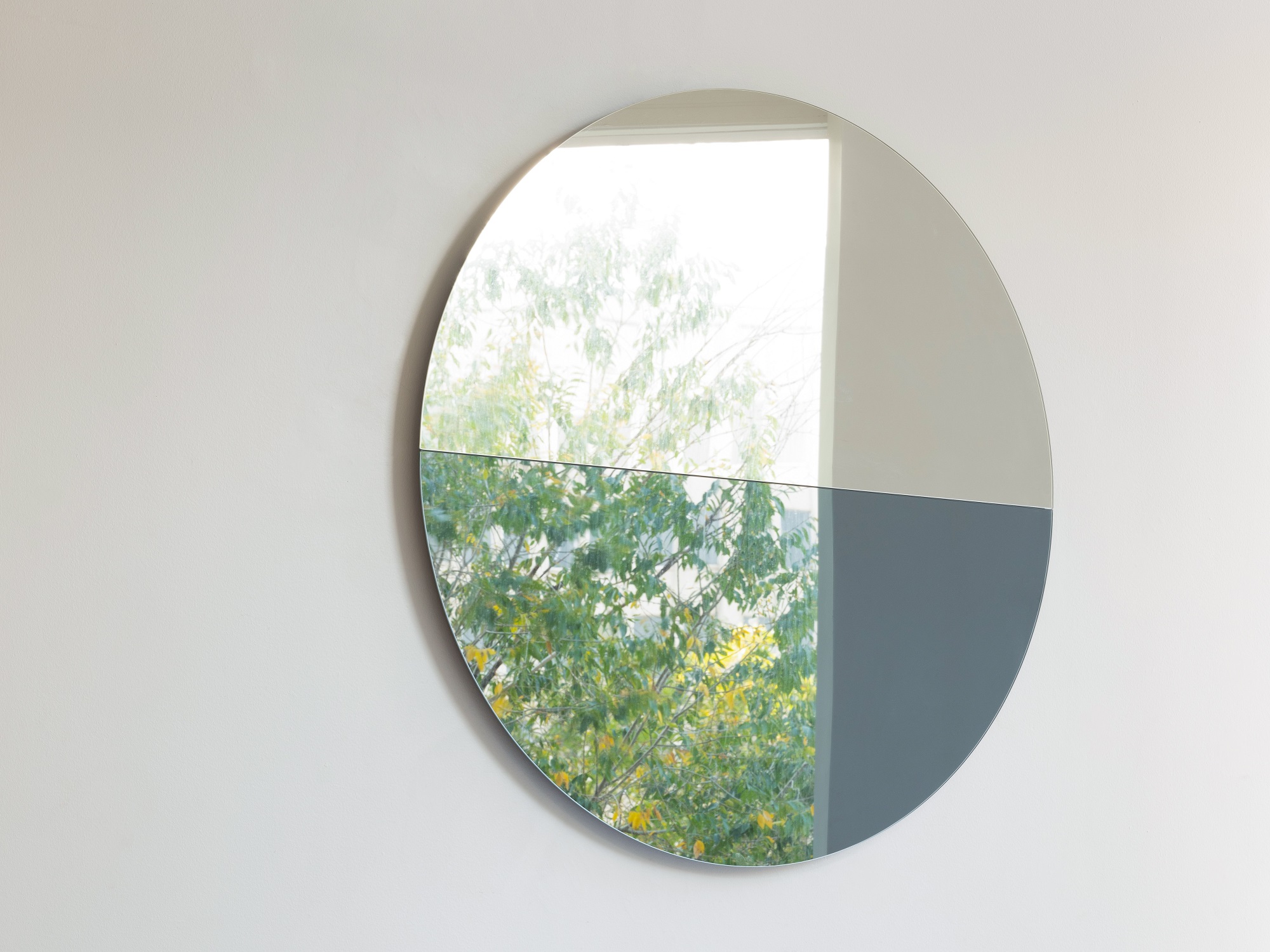 Silver and blue round wall mirror with tree in its reflection