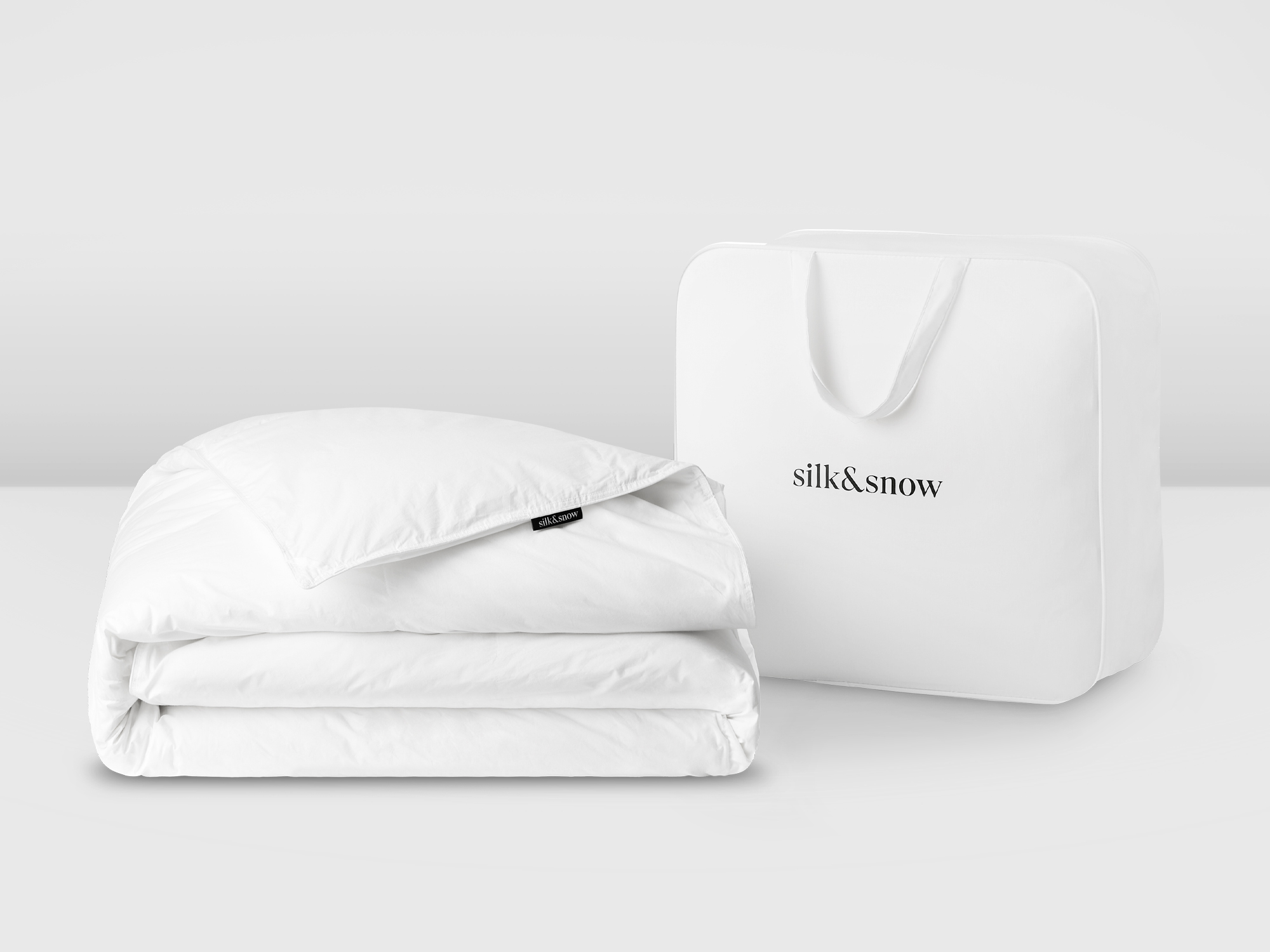 Folded white down duvet with tote bag side view