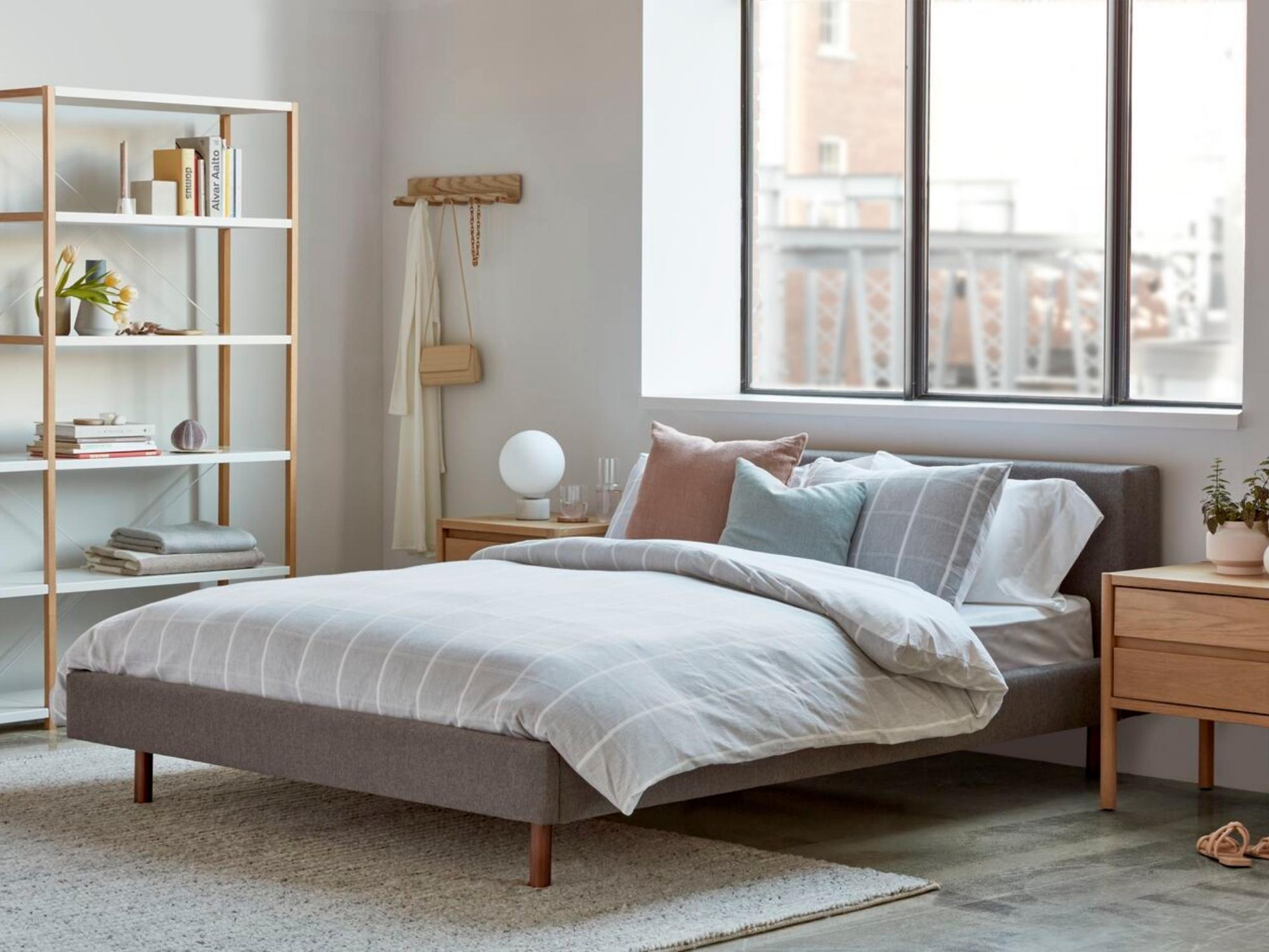 Braided wool rug under upholstered bed frame in bedroom