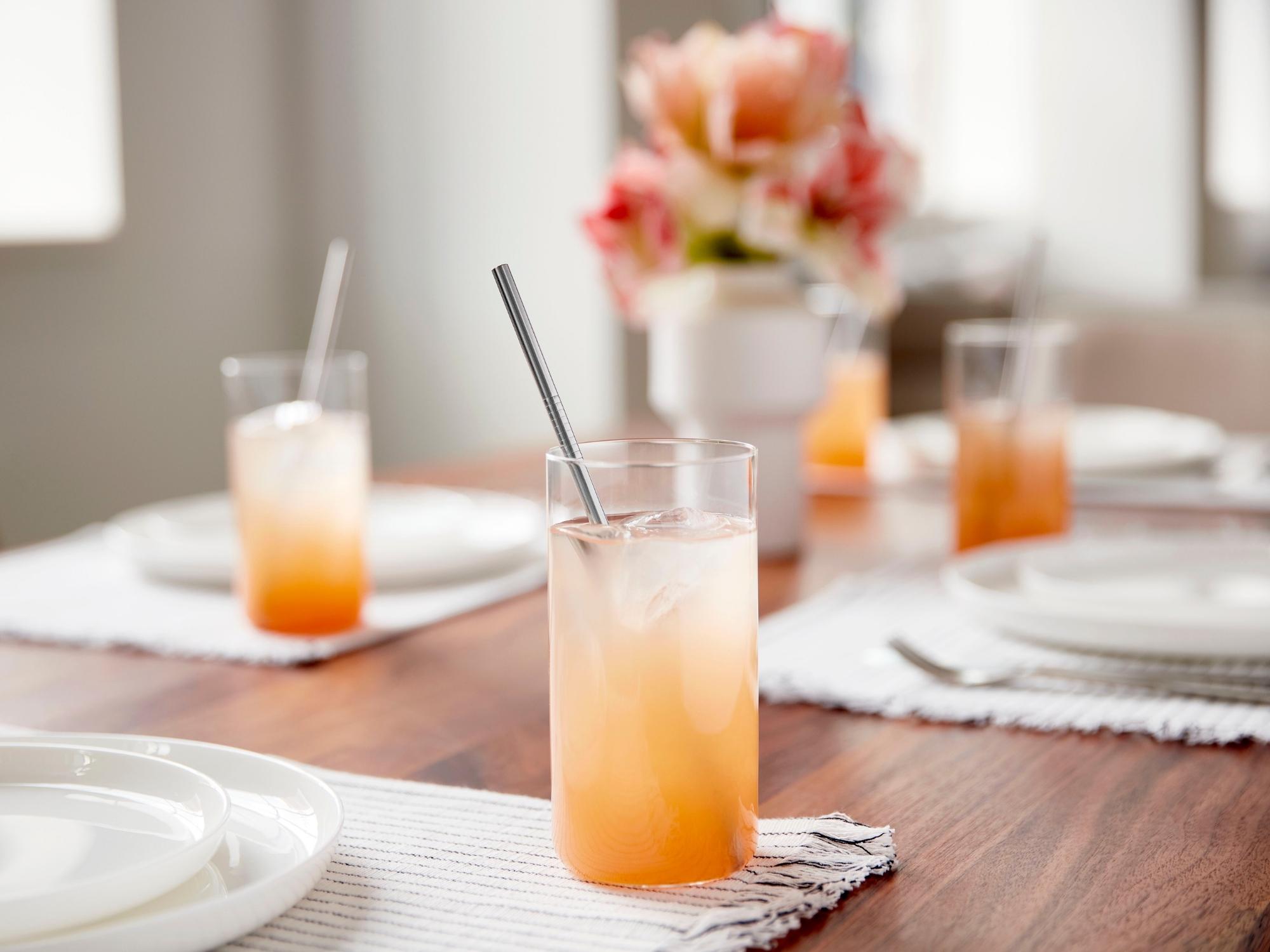 Highball glass with metal straw in it on table set for a meal