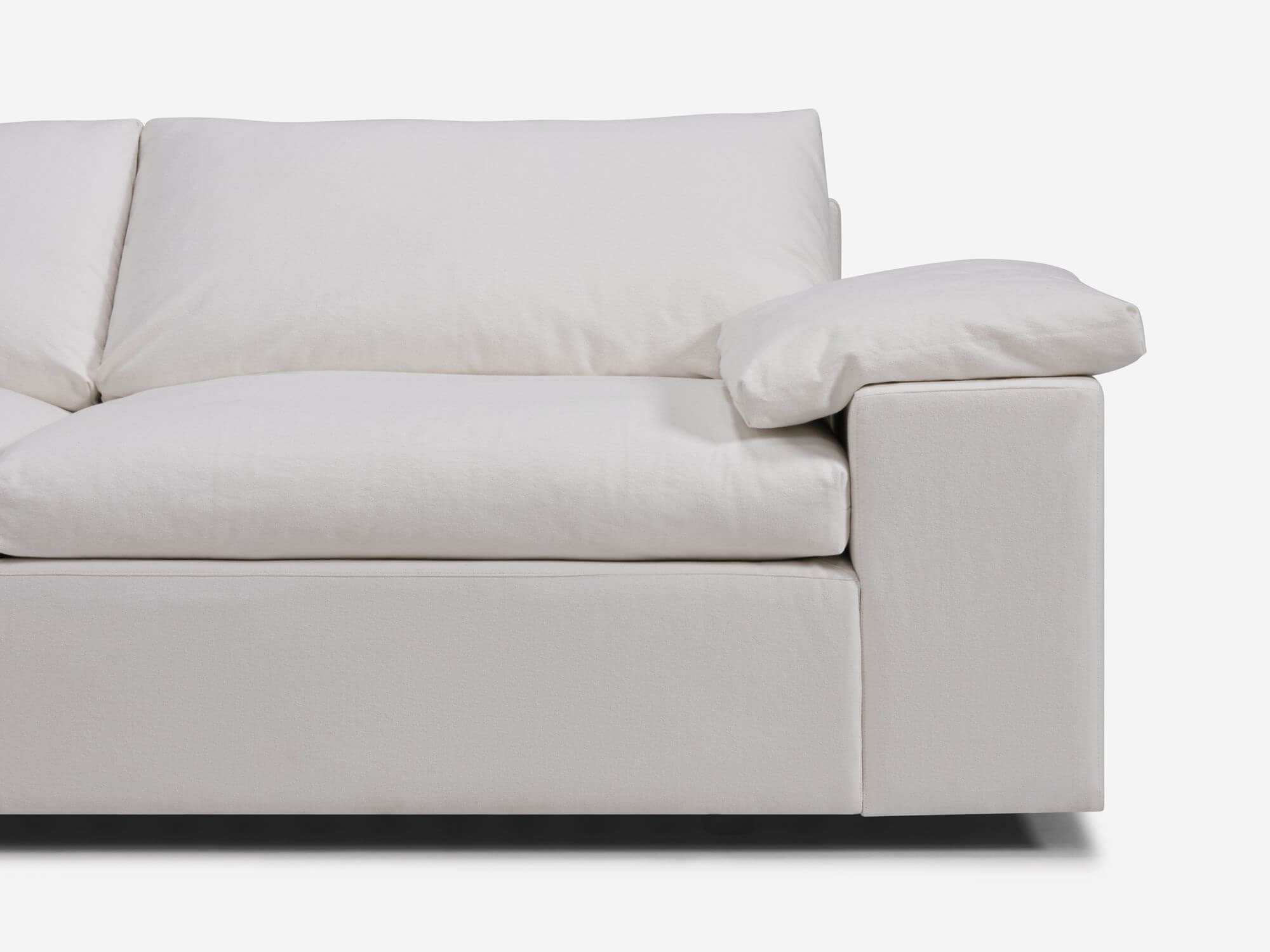 Detail view of white sectional sofa with left hand chaise, pillow and wide arms