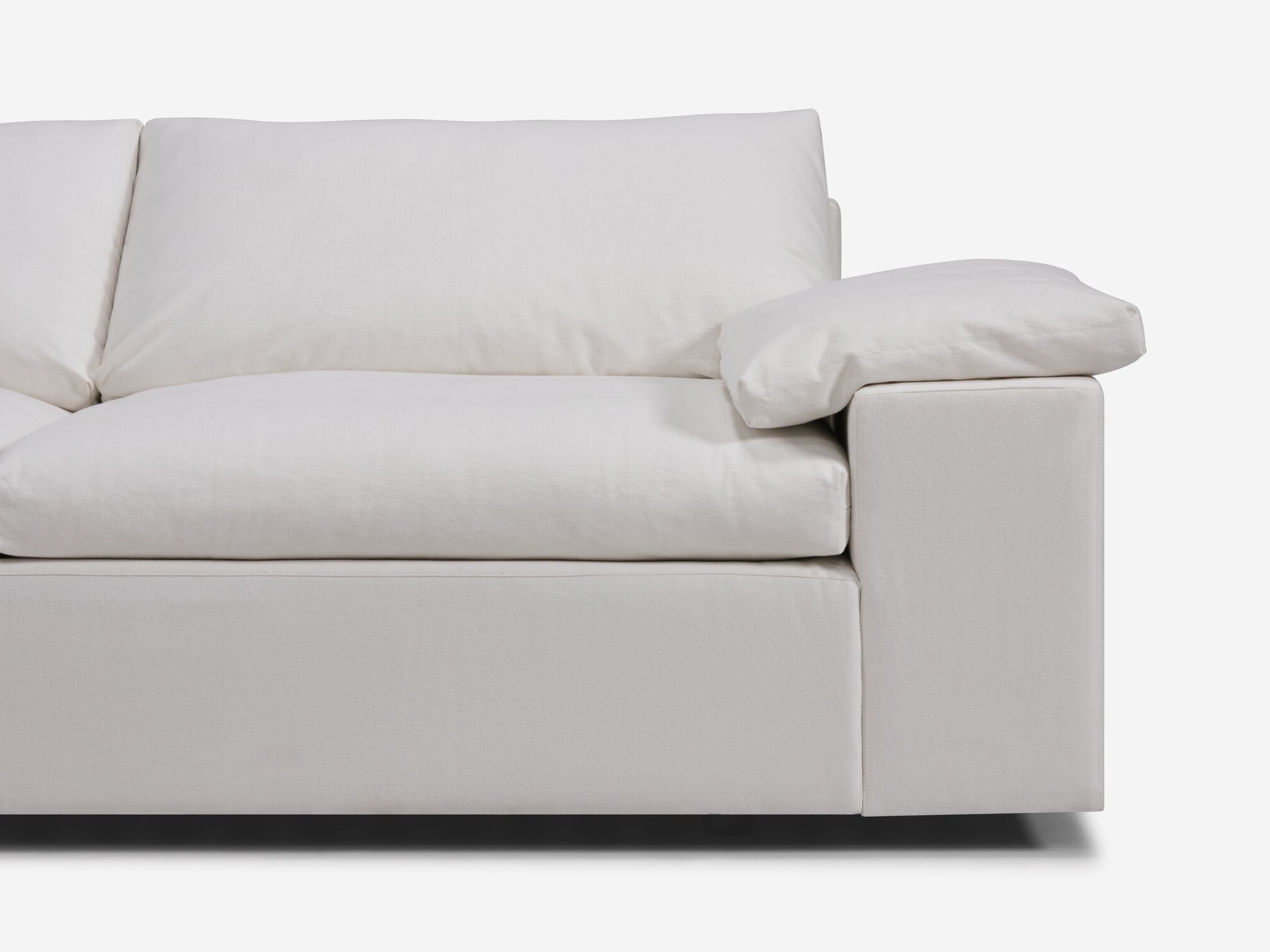 Detail view of white sectional sofa with left hand chaise, pillow and wide arms