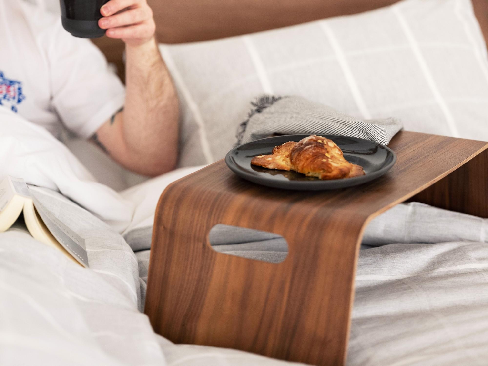 Black side plate on walnut bed tray on grey bed sheets