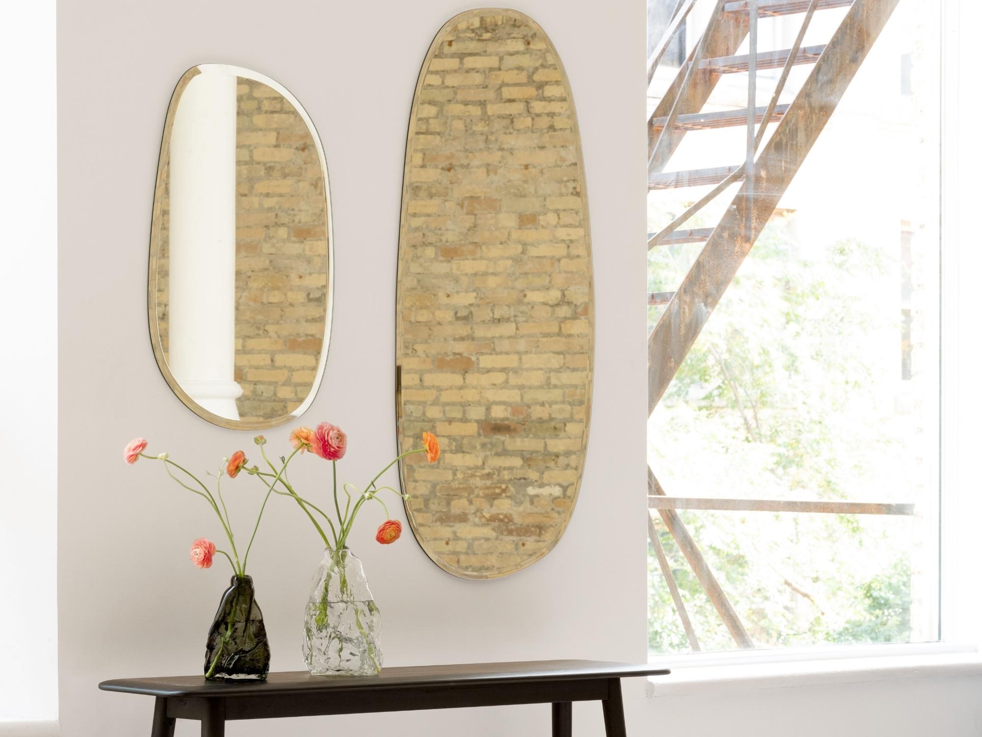 Two mirrors on wall above dark console table between windows