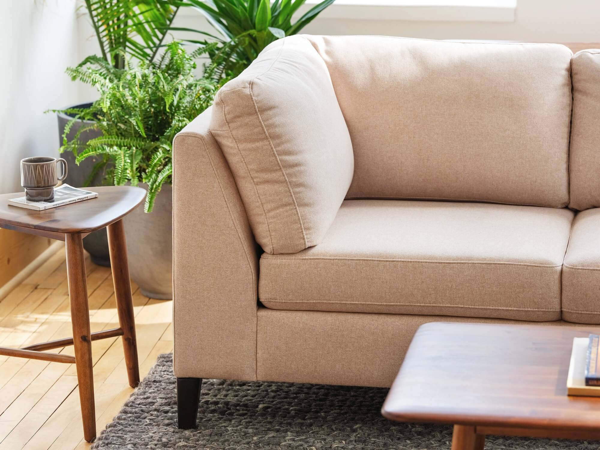 Arm of modern boho beige sofa with walnut coffee and end tables