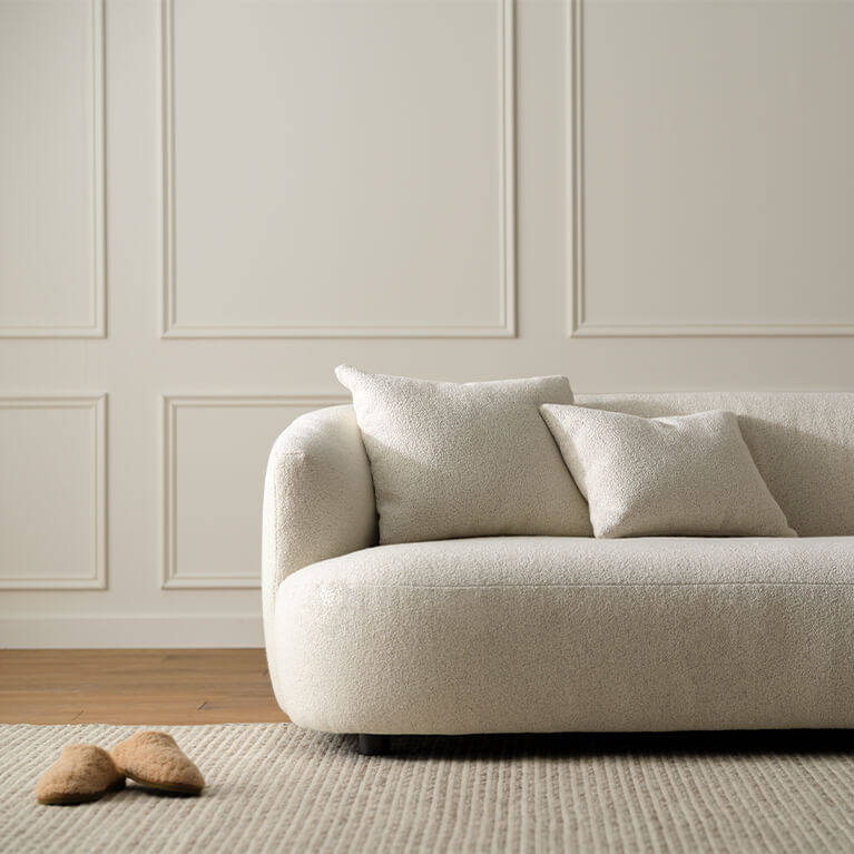 Detail view of a white fabric sofa is shown in a living room. Link to Sofas