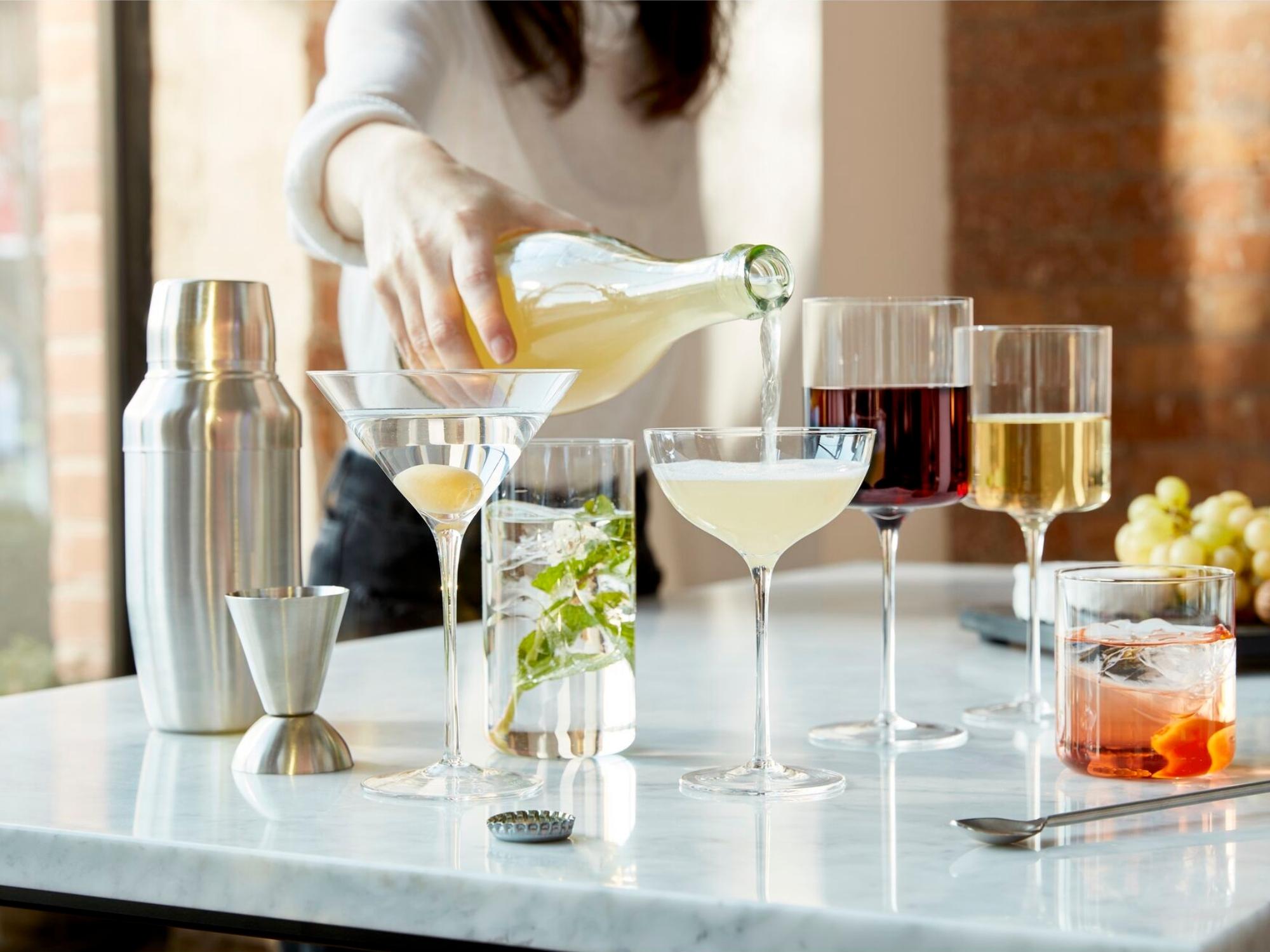 Silver jigger with shaker and clear glassware on marble table