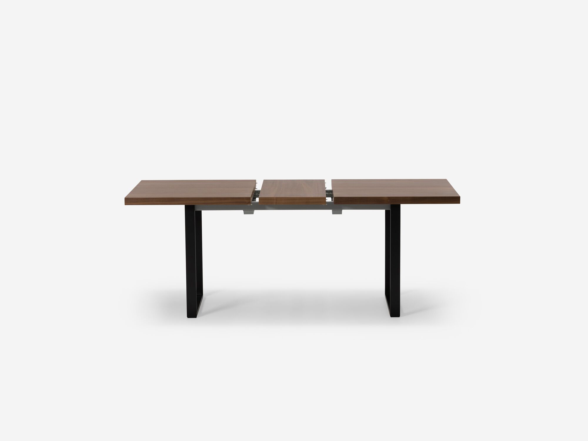 Side view of expandable dining table with black legs and walnut top with one leaf separated