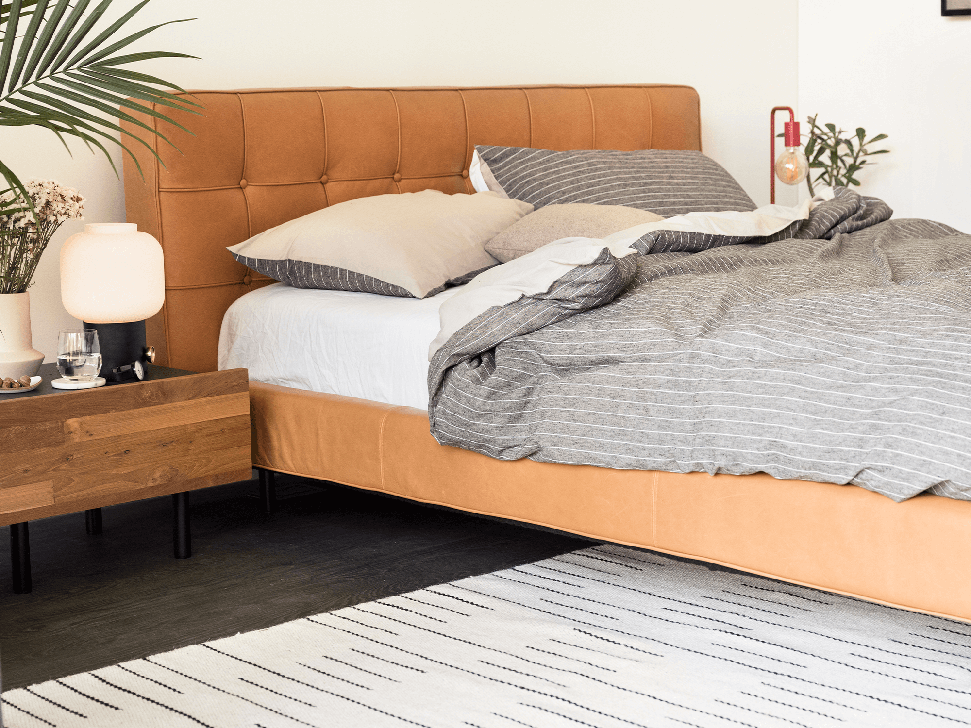 Reclaimed teak nightstand sits beside a brown leather upholstered bed