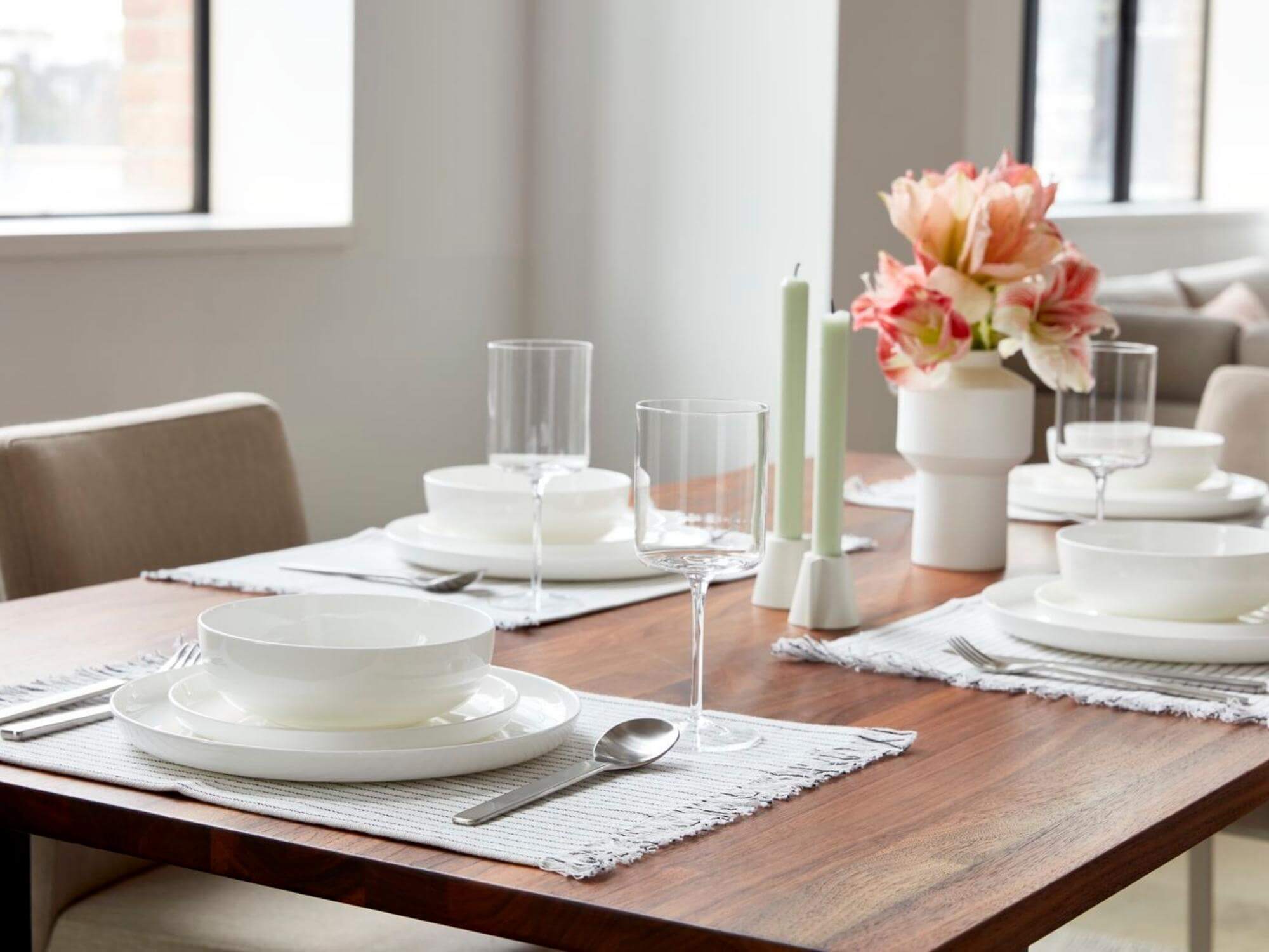 White pasta bowls on side and dinner plates on walnut dining table