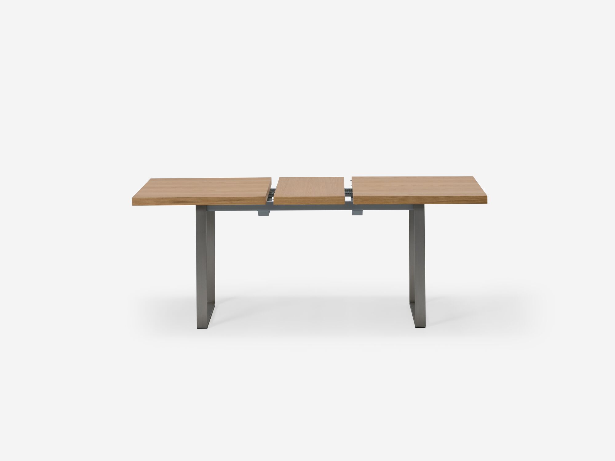 Side view of expandable dining table with stainless steel legs and oak top with one leaf separated