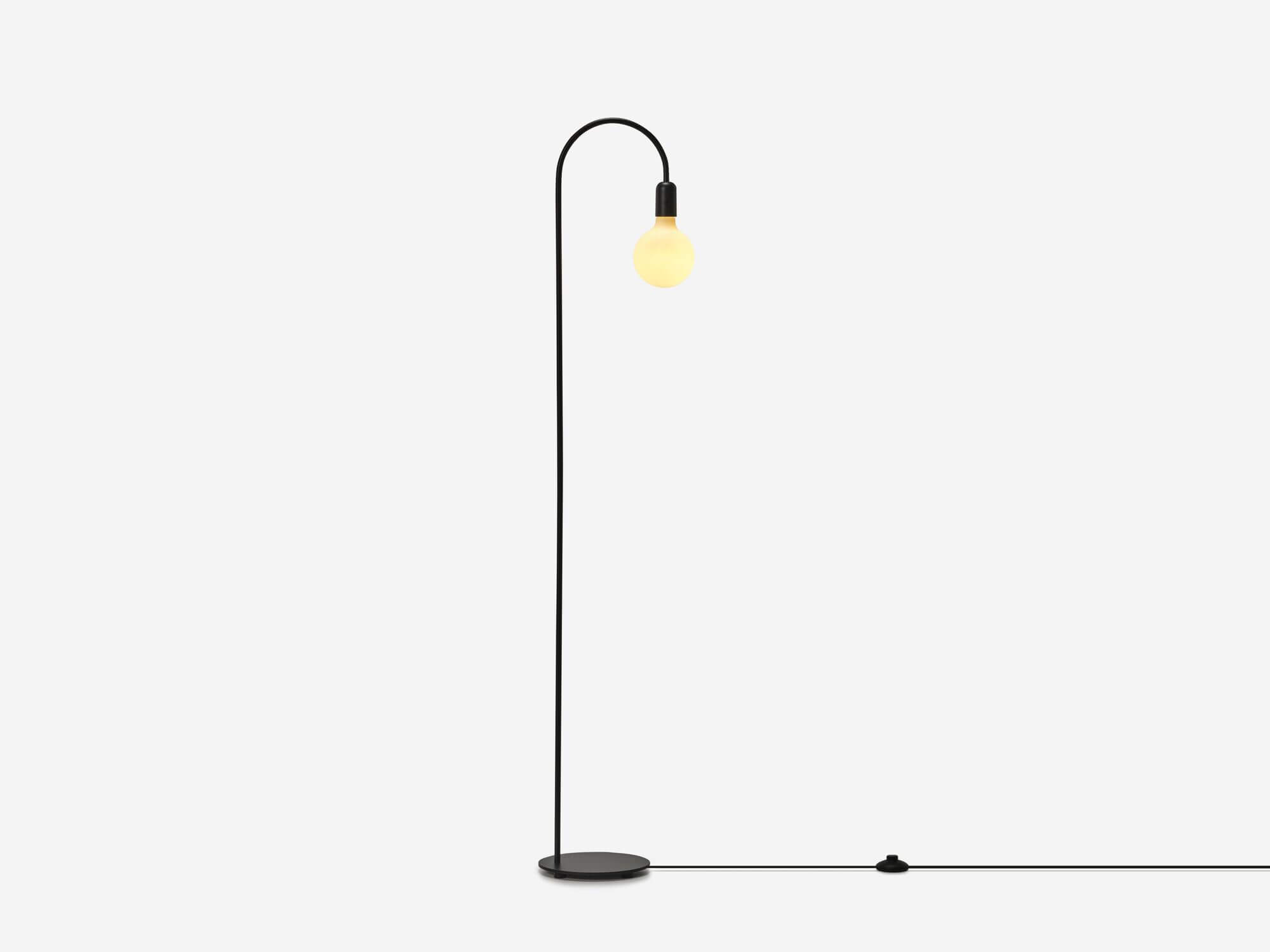 Black arched floor lamp with light on side view