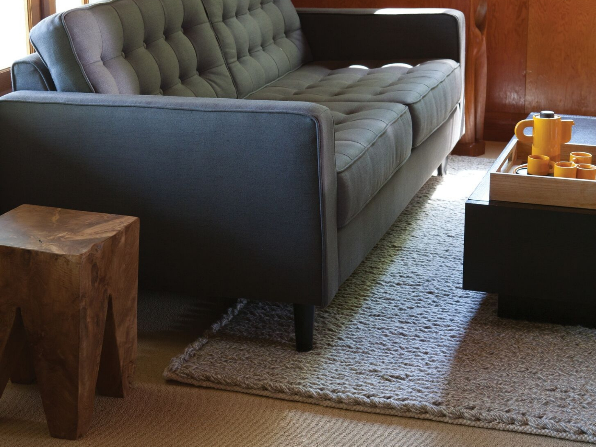 Solid teak wood end table beside mid century couch