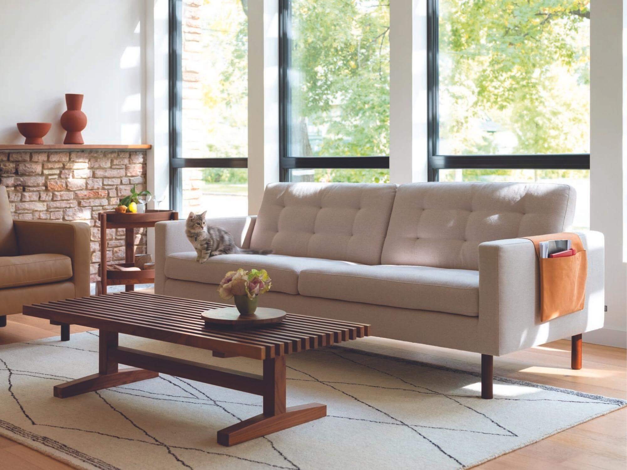 Brown saddle bag over arm of beige mid century sofa in living room