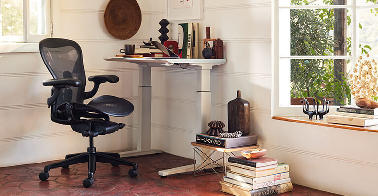 Black Aeron Herman Miller stool is displayed in a home office. Link to Herman Miller sale page