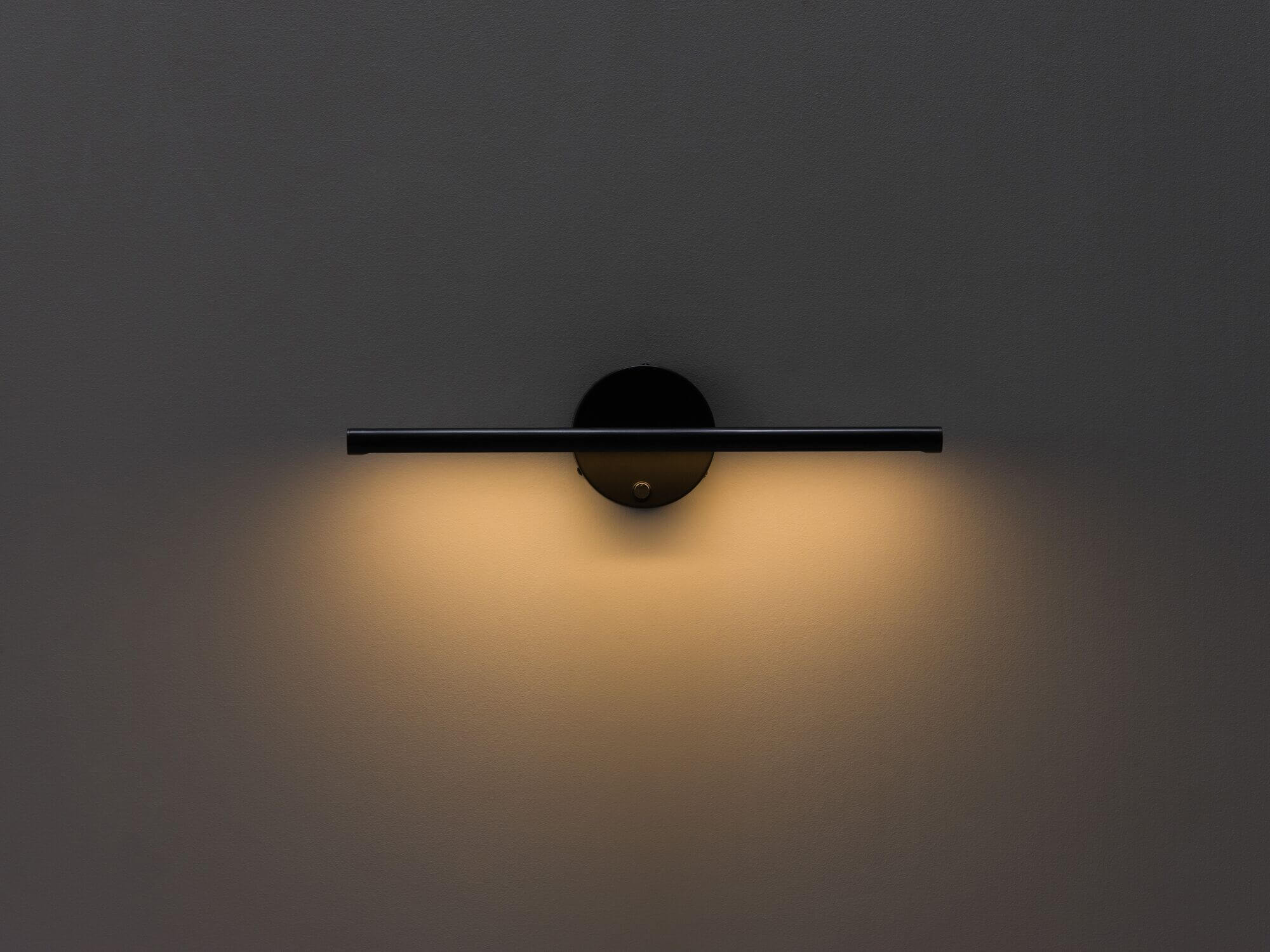 Front view of black slim wall lamp with light on high