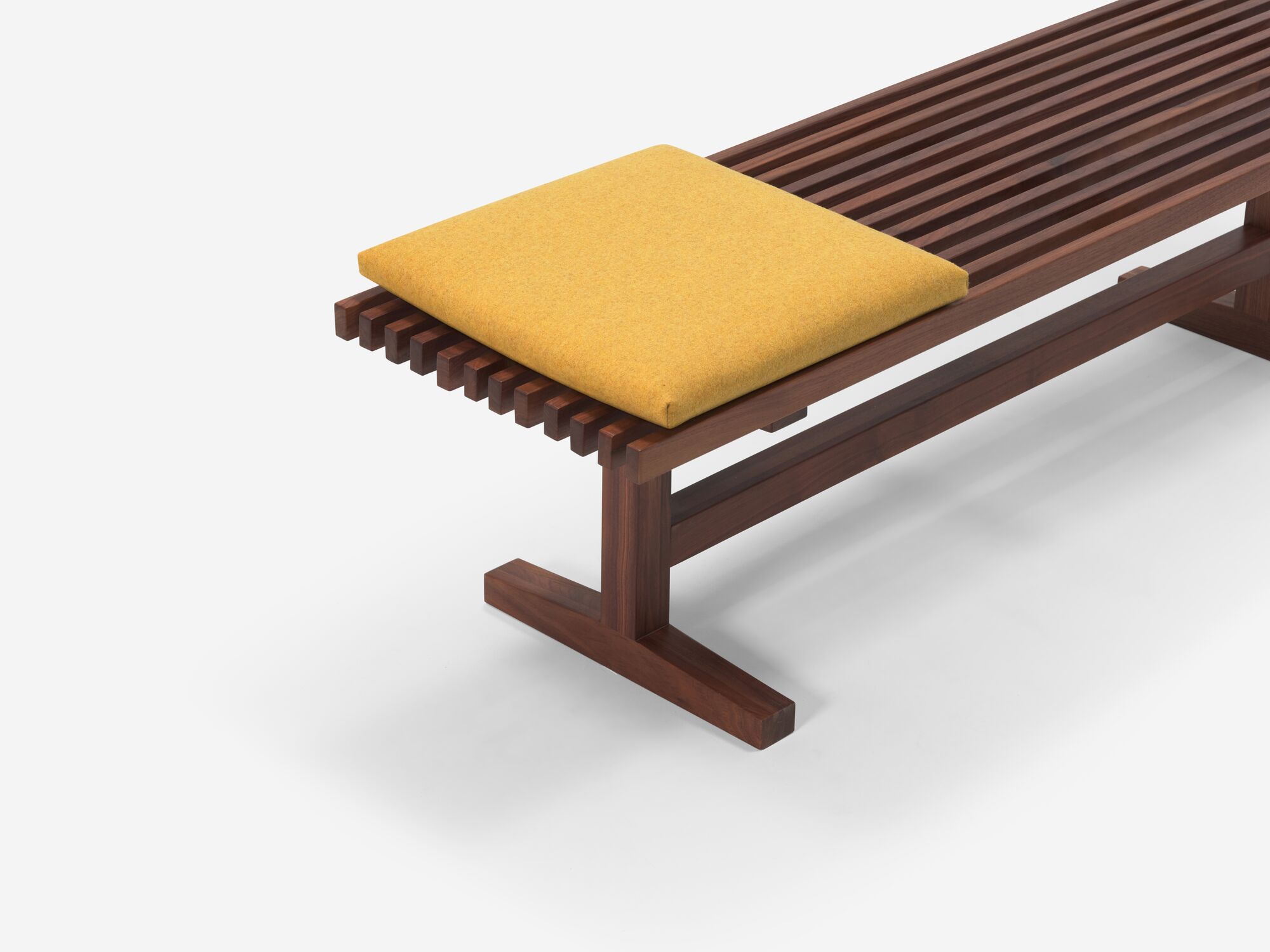 Square yellow cushion on walnut bench top angle view