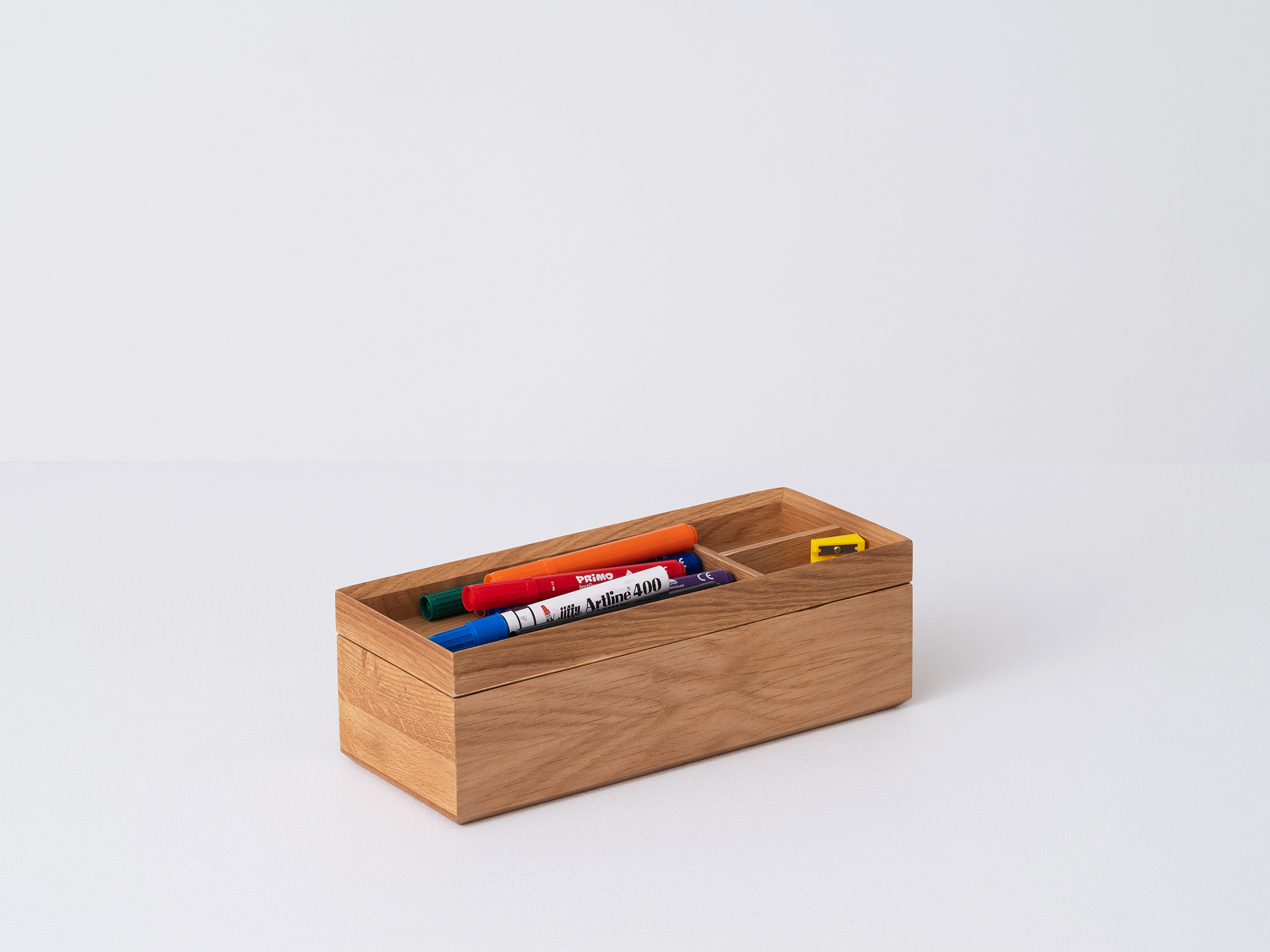 Angled view of the large wooden Draft Pencil Box in oak with pencils in the top