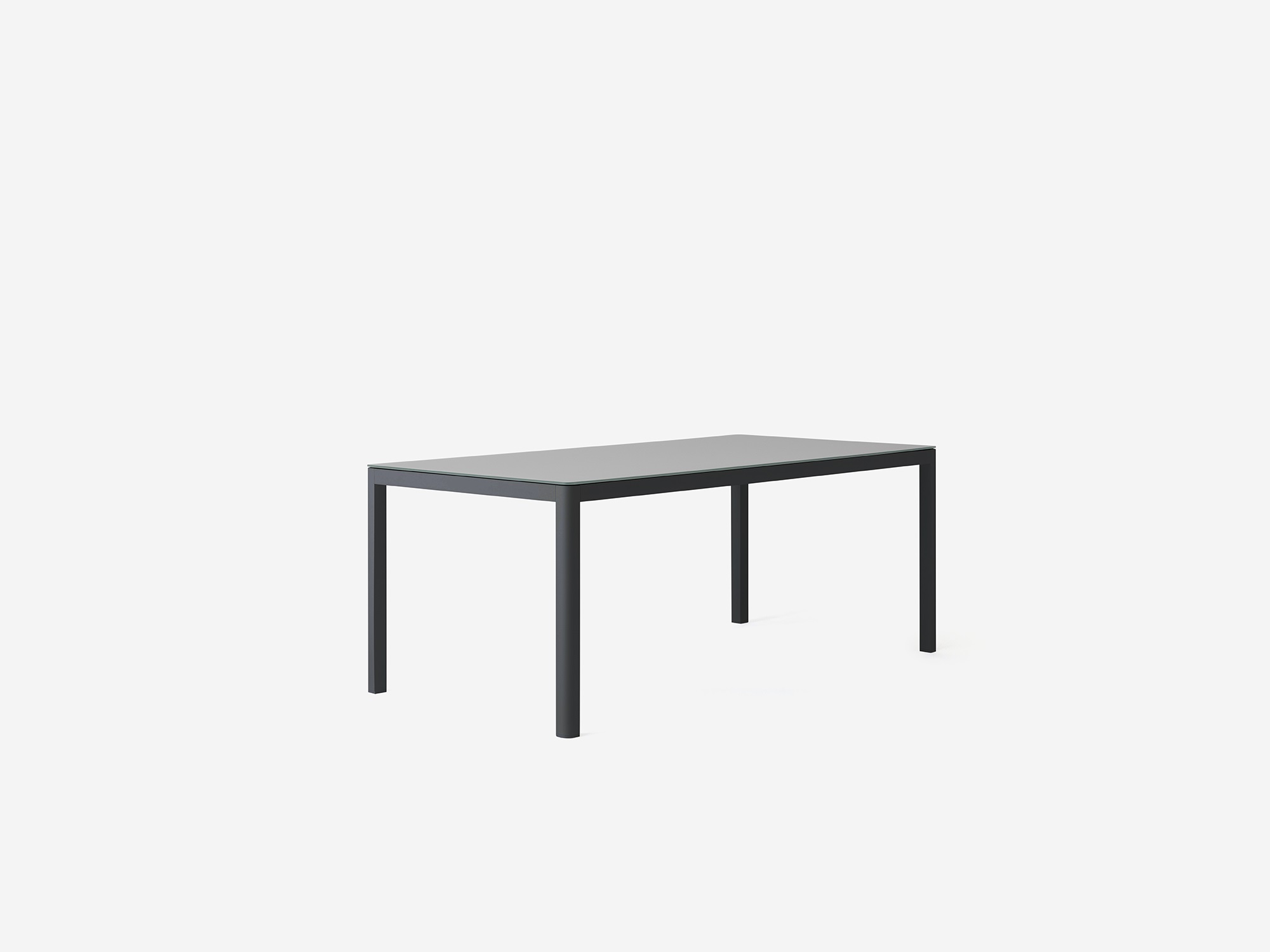 Angled view of the Cape outdoor dining table with a grey glass top and black metal base