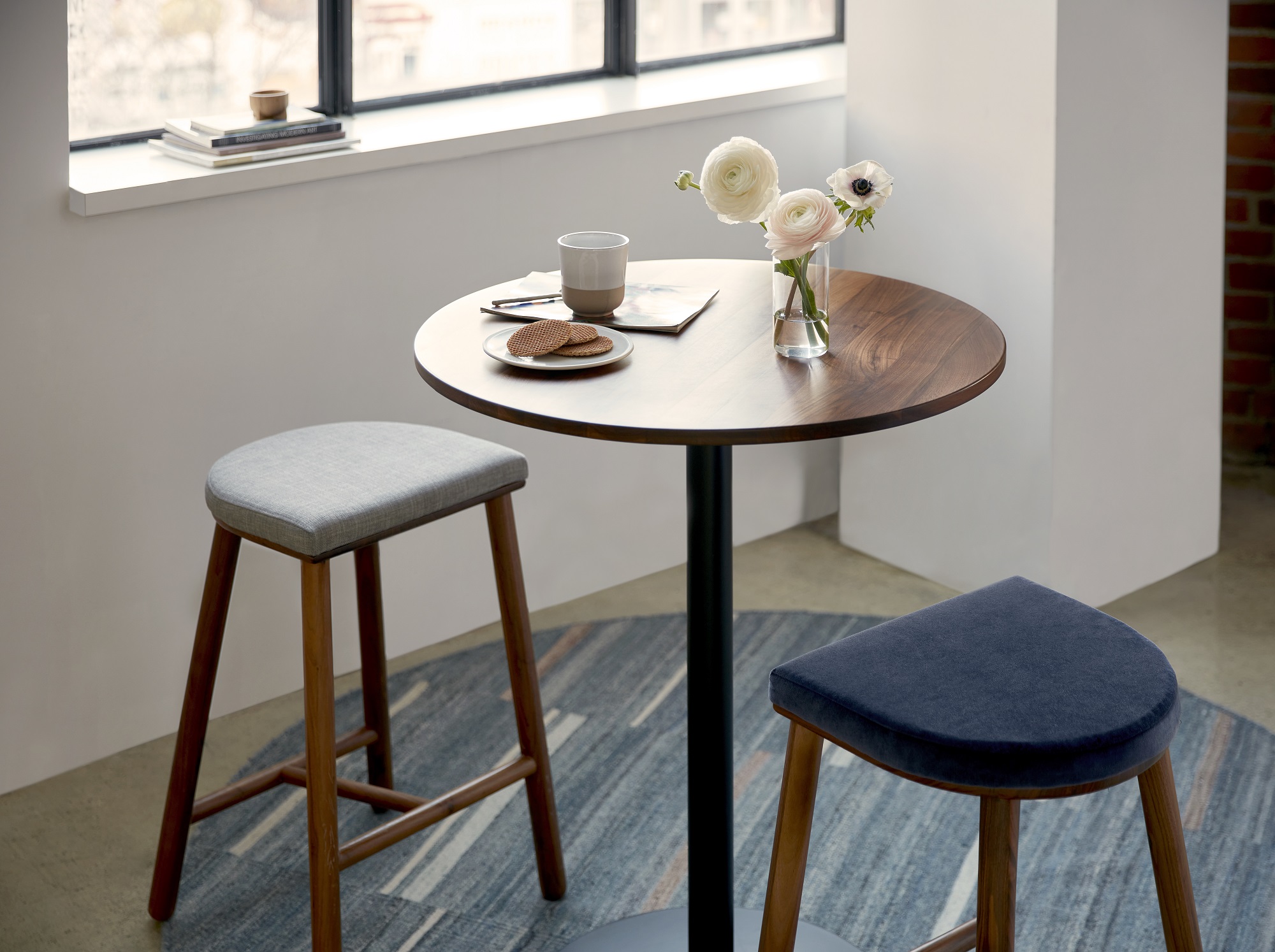 Beige and blue fabric counter stools around tall round table set for coffee