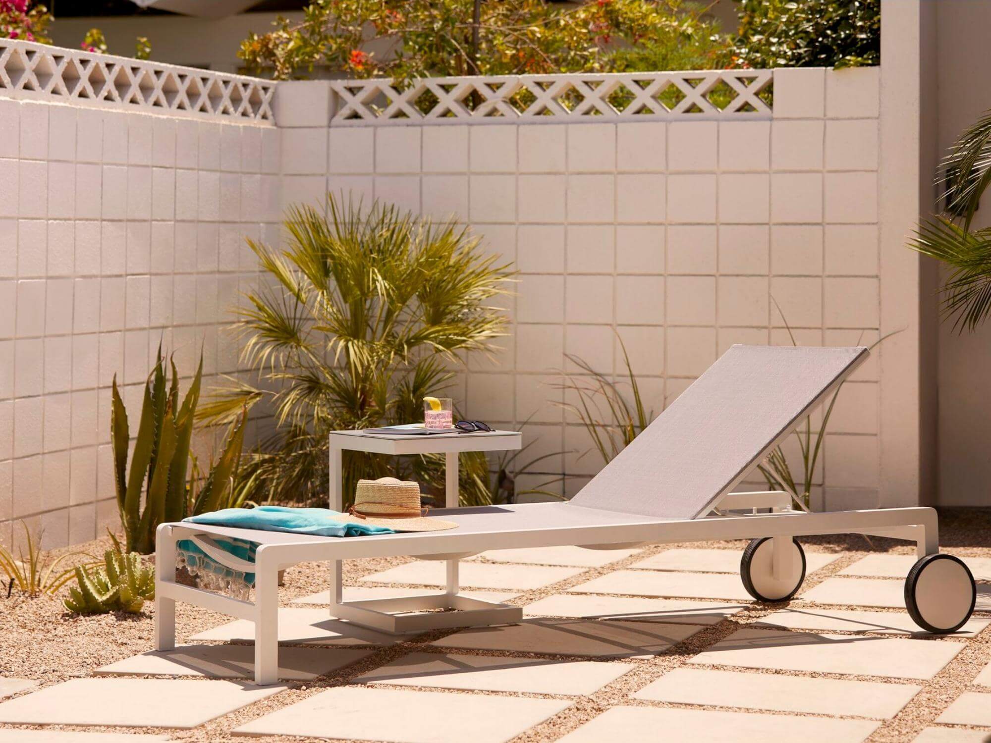 Grey and white outdoor side table with chaise on a pool deck