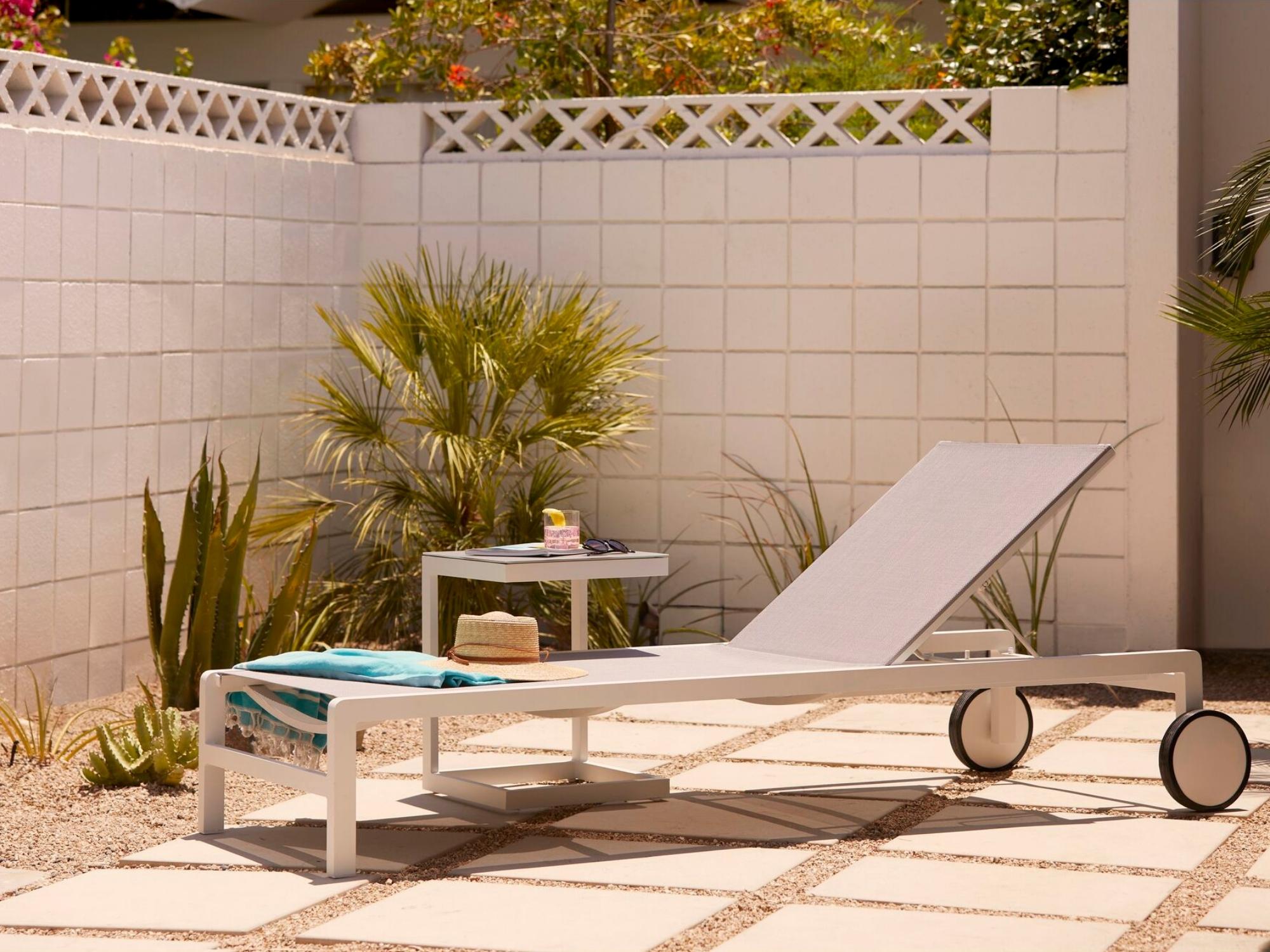 Grey and white outdoor side table with chaise on a pool deck