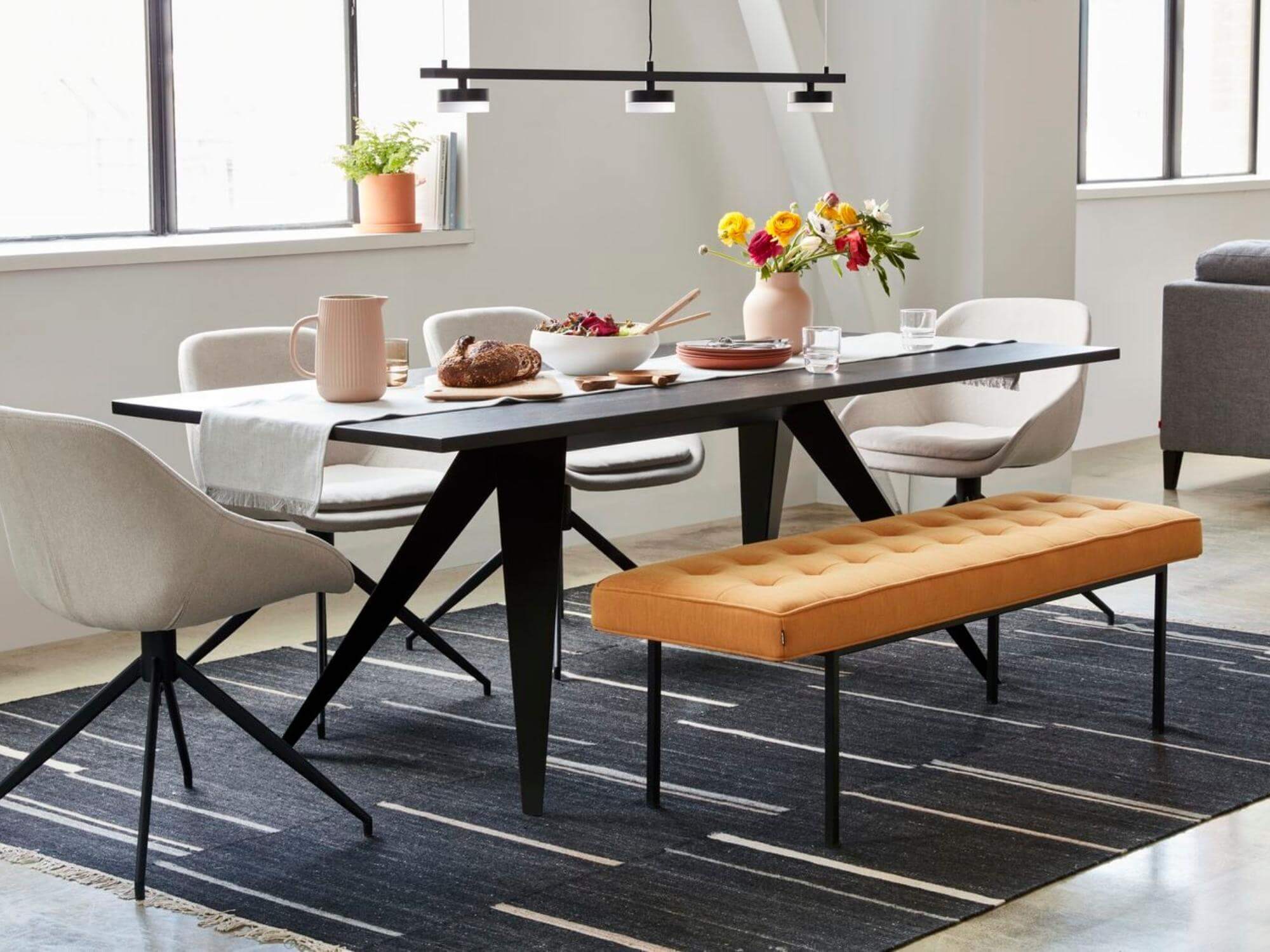 Black striped dining room rug under orange dining bench and dining table