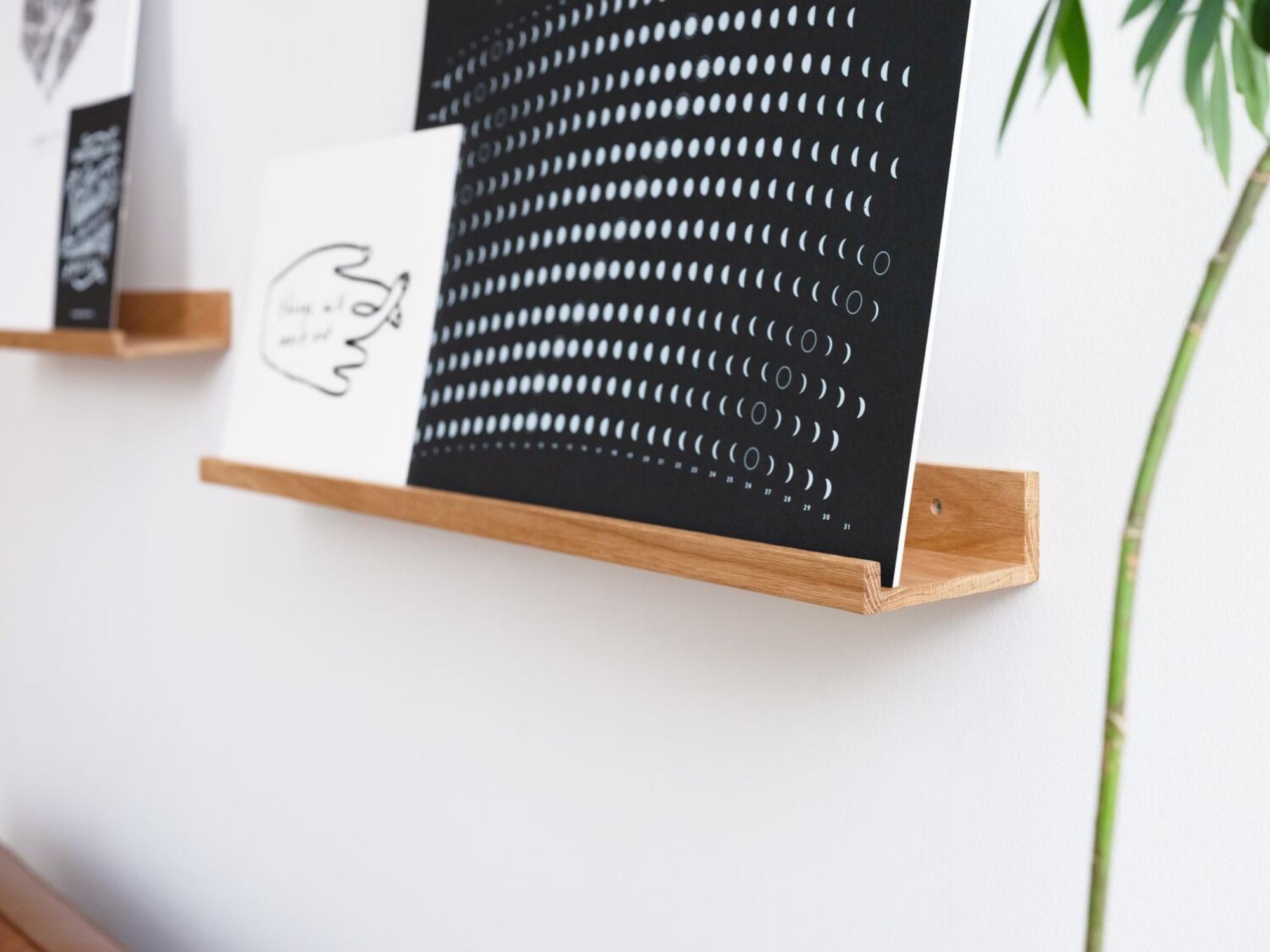 Detail view of solid wood art ledge with black and white prints on it