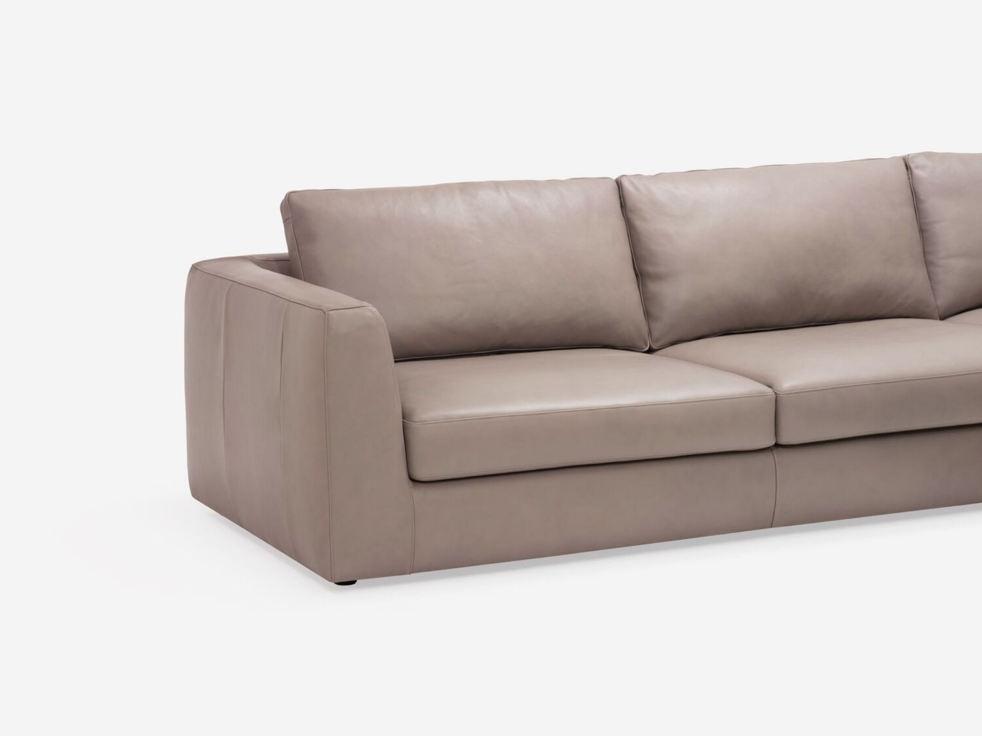 Angled view of the modern sectional couch in beige leather with right hand backless chaise