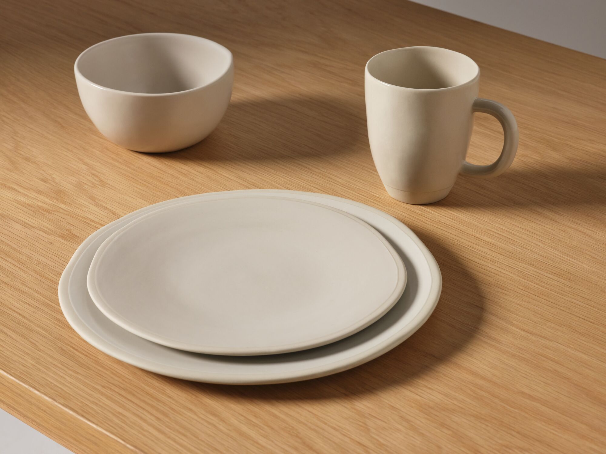 Assiettes en grès avec bol et tasse sur comptoir en chêne