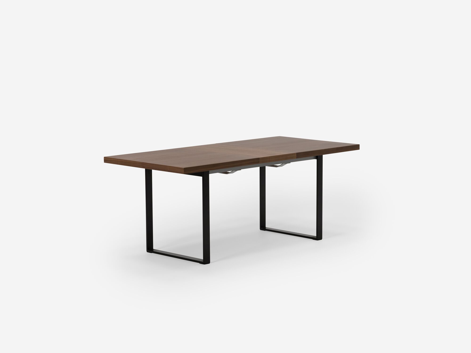 Expandable dining table with black legs, walnut top and one leaf corner view