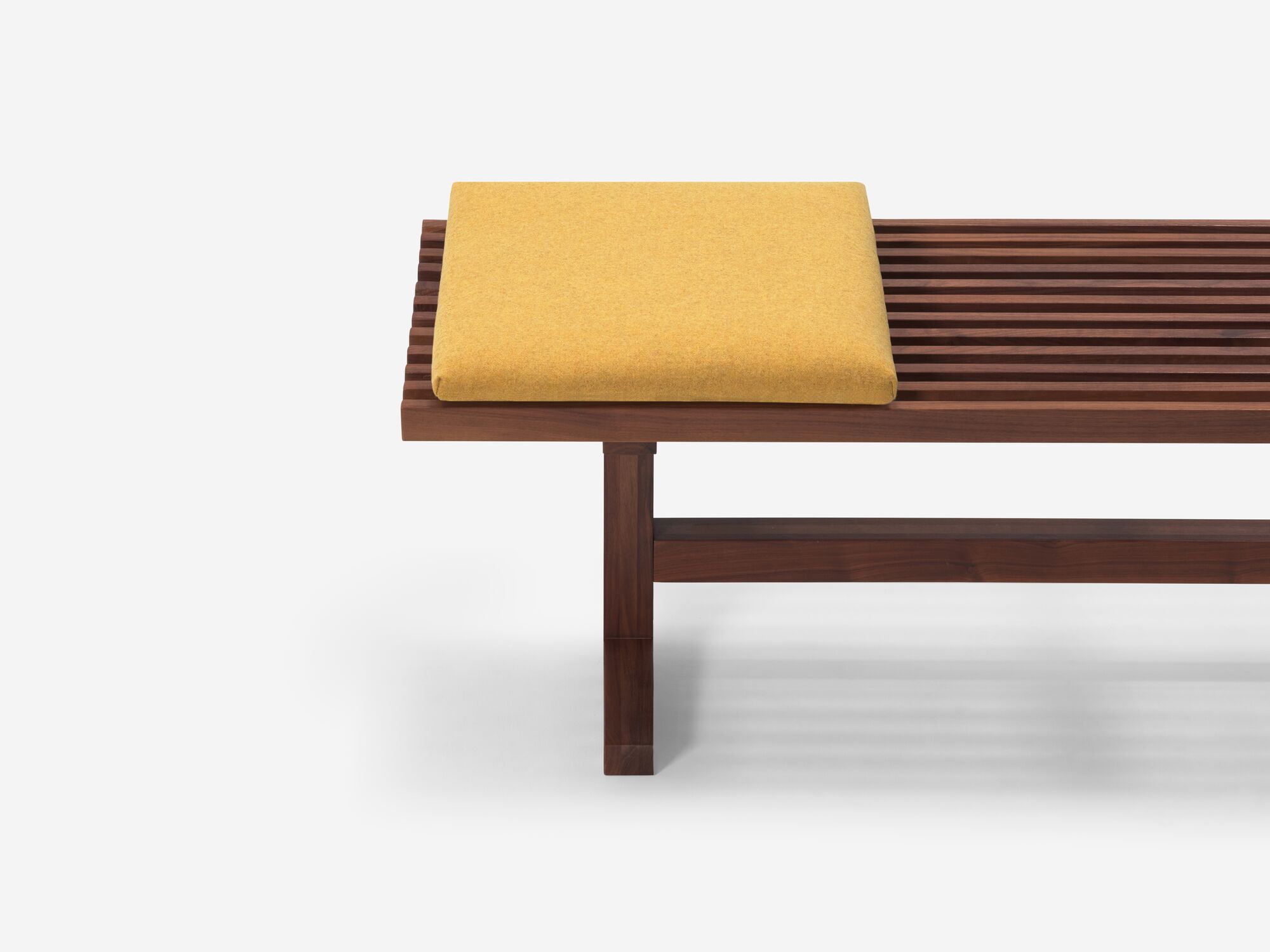 Square yellow cushion on walnut bench front view