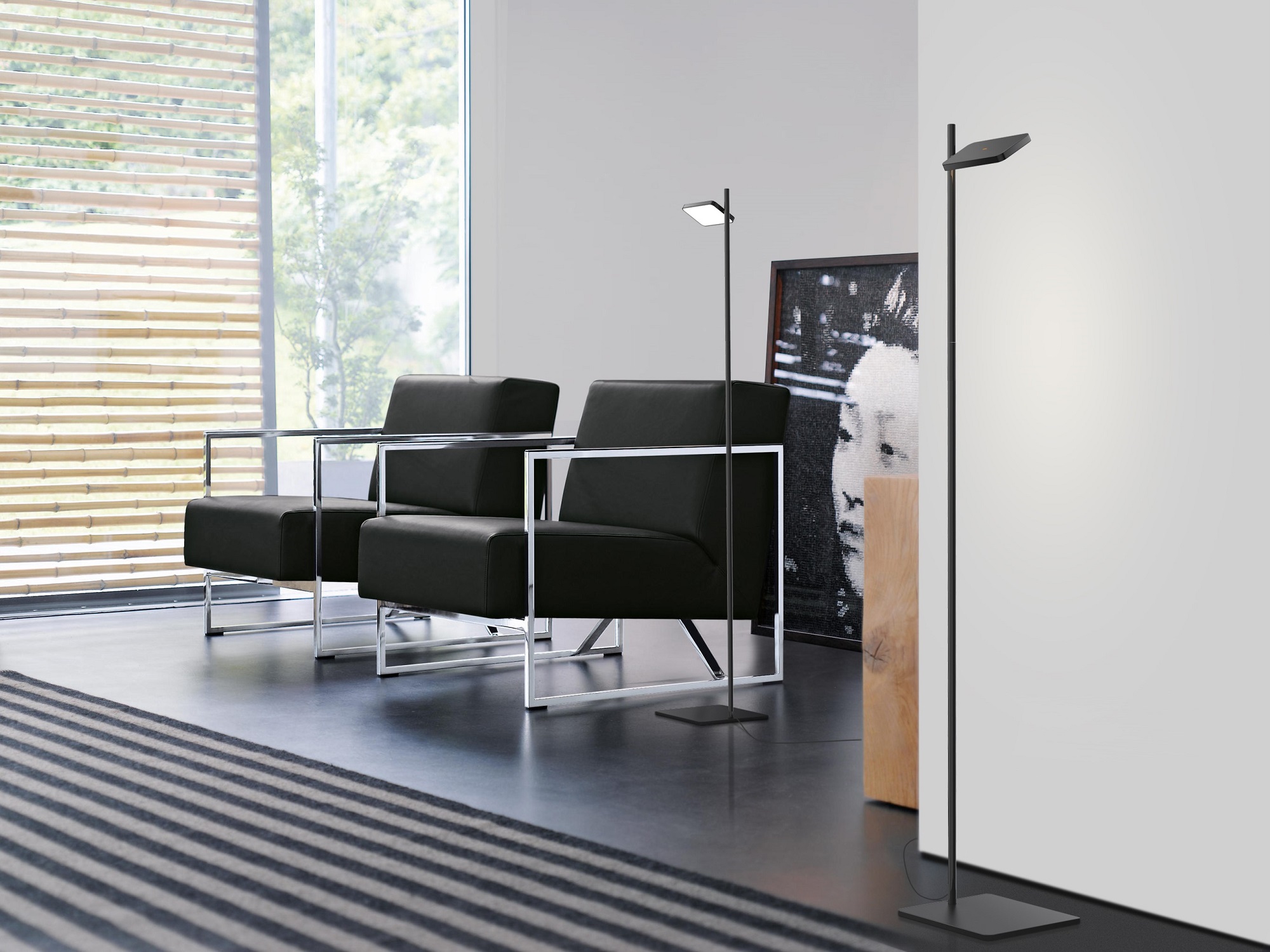 Talia floor lamp in black sits beside black leather chairs in a living room