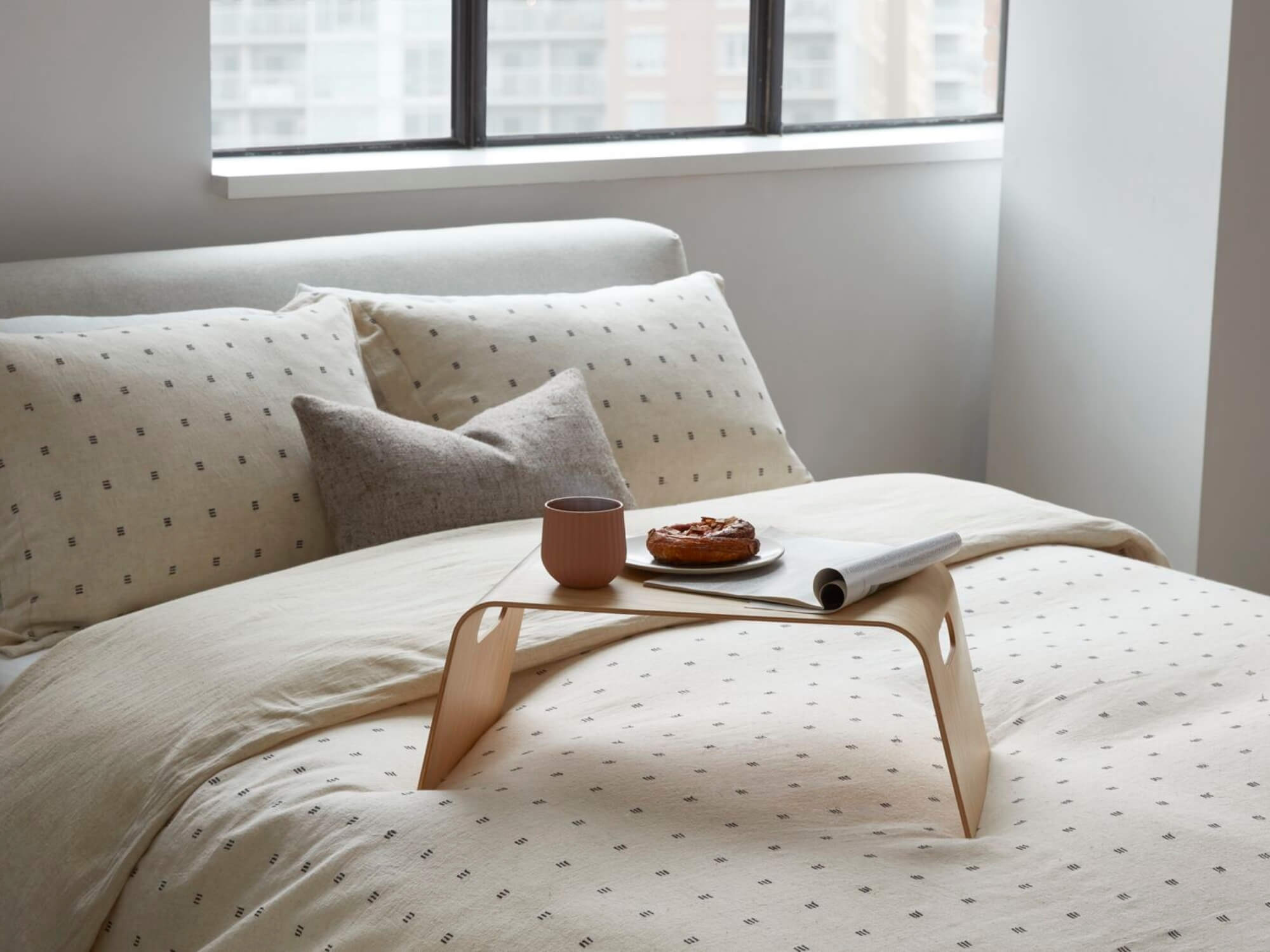 Gray lumbar pillow on an upholstered bed with beige sheet set