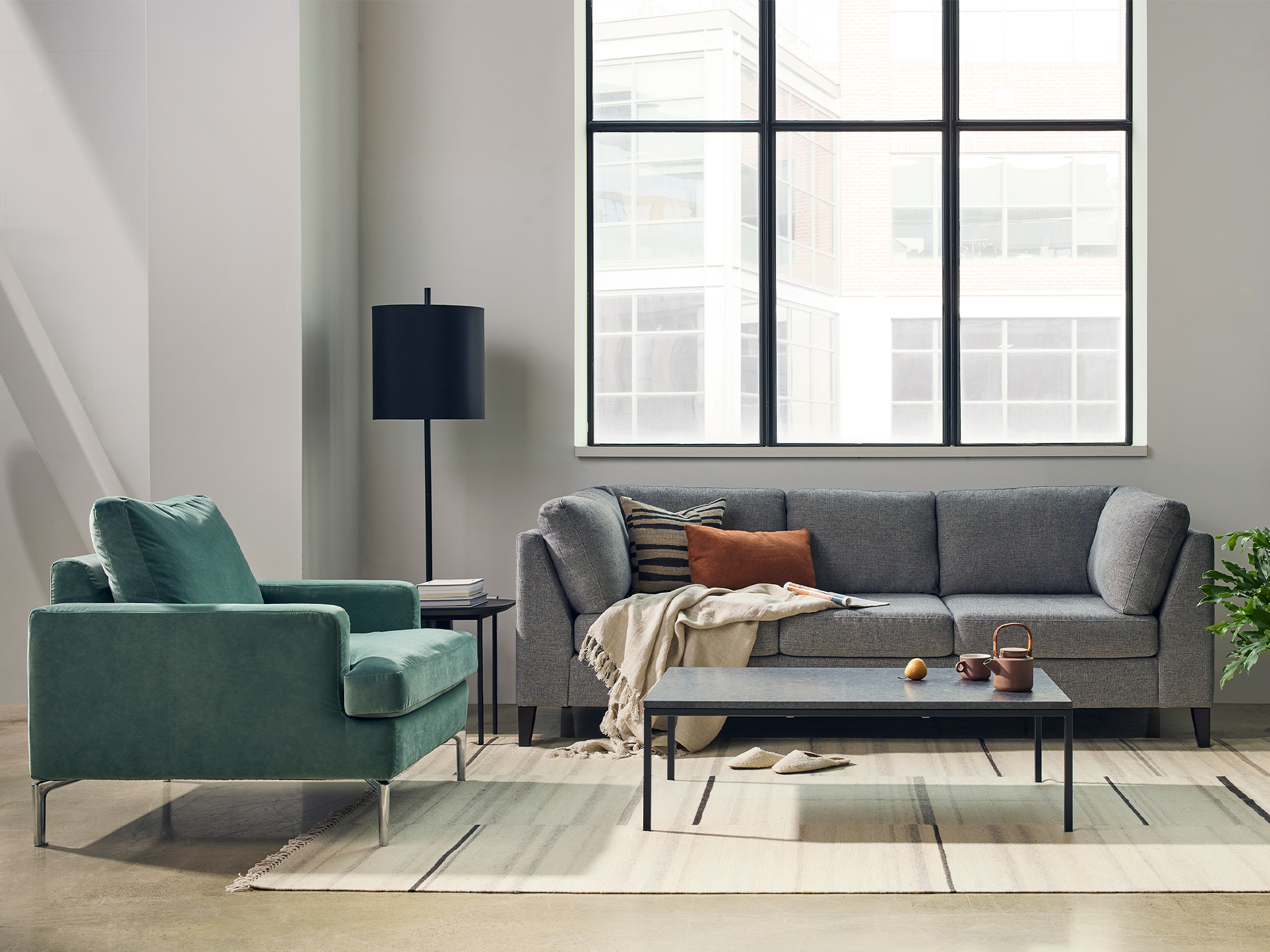 Green armchair with a gray sofa sit on a beige rug in a modern living room