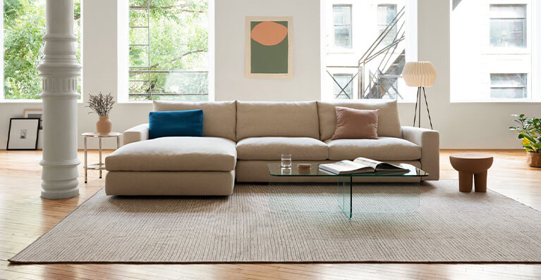 A beige fabric sectional sofa sits in a living room. Link to EQ3 seating category
