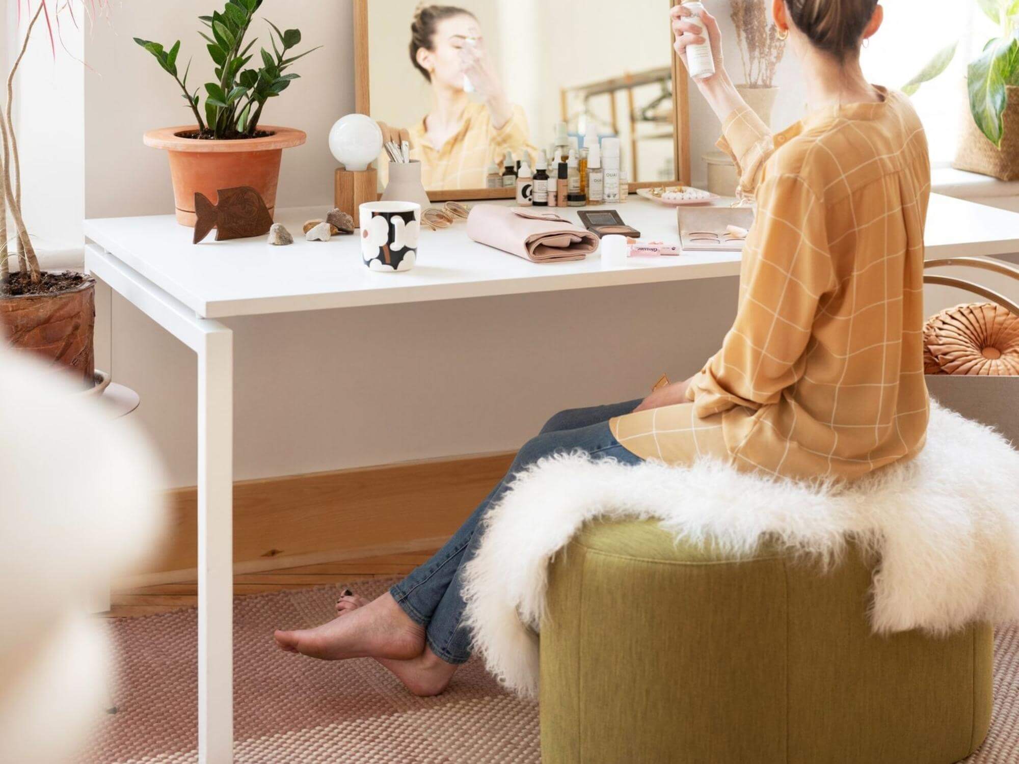 Oval green ottoman with woman sitting on it at vanity table